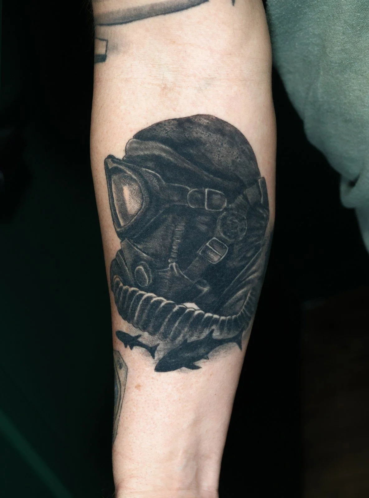 Cover-up before - a black and gray gas mask and shark tattoo on the forearm.