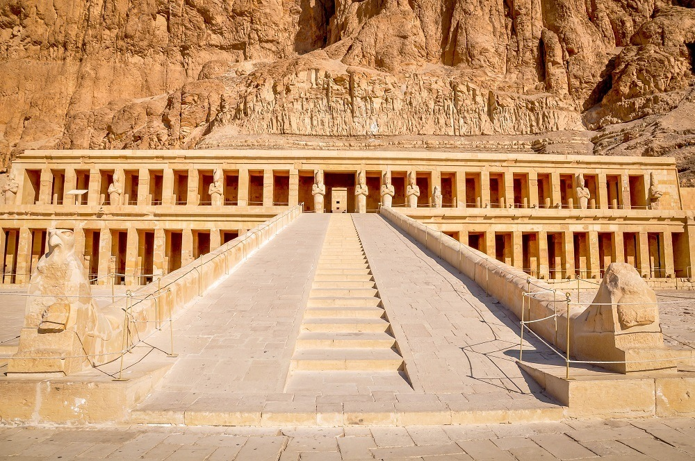 The central ramp and monumental facade of the Temple of Hatshepsut beneath the desert cliffs