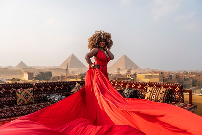 A woman in a flowing red dress posing in front of the Egyptian pyramids