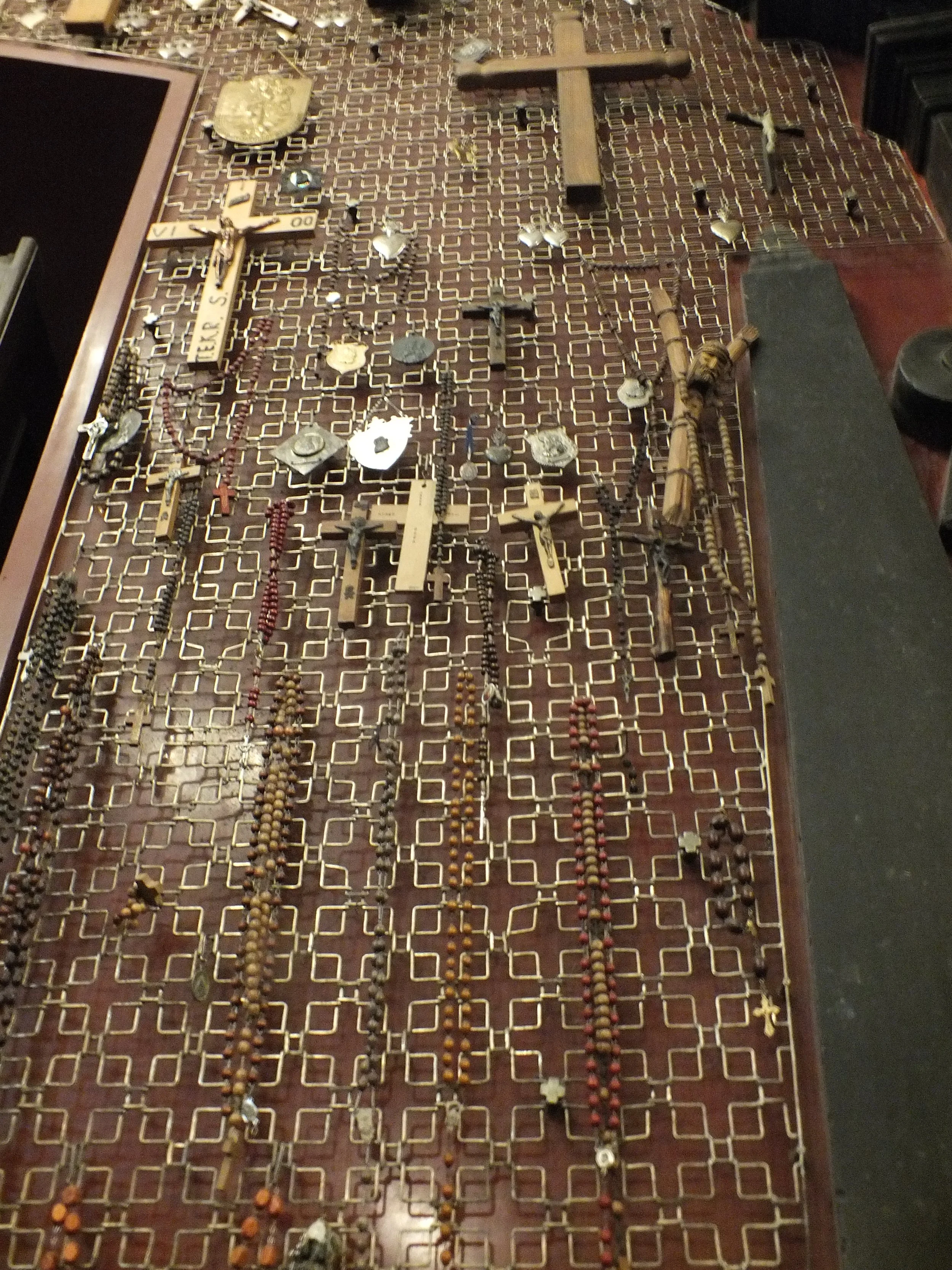 Rosaries, crosses, and other votive objects displayed on a metal grille at Jasna Góra