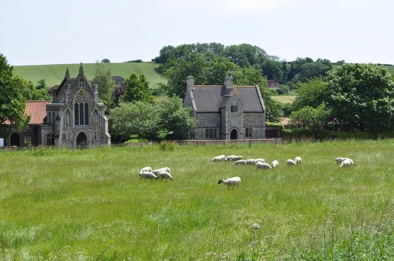The Slipper Chapel and presbytery seen across a field at Houghton St Giles.