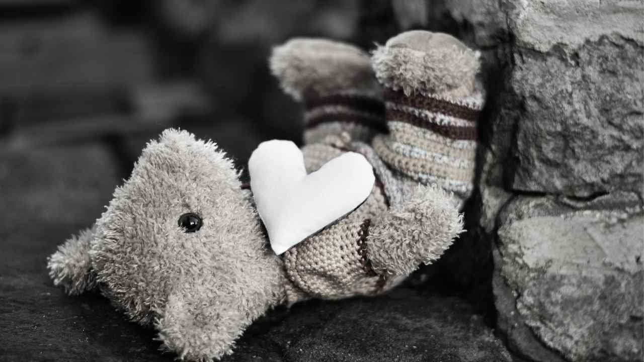 A knitted toy holding a white heart.