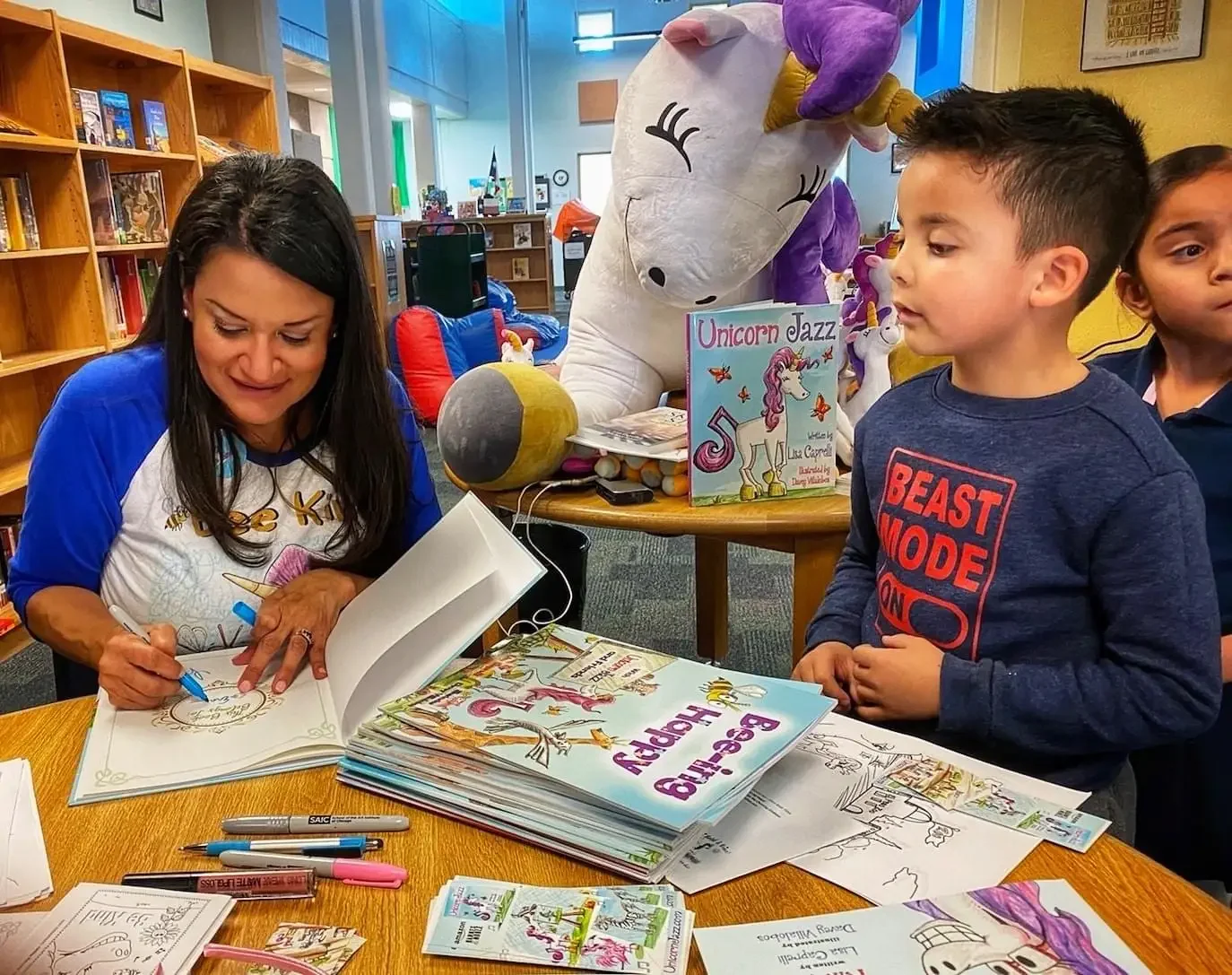 Lisa Caprelli signing a Unicorn Jazz book for a young reader at a library visit