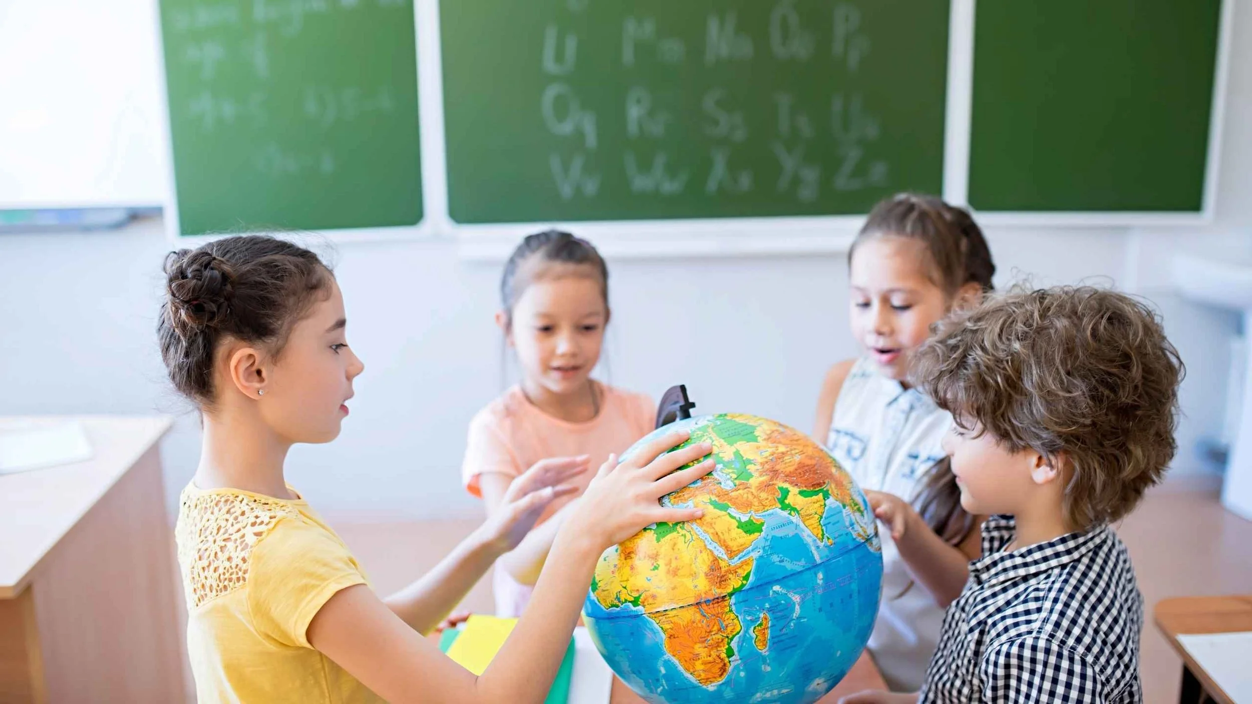Children exploring a globe in a classroom