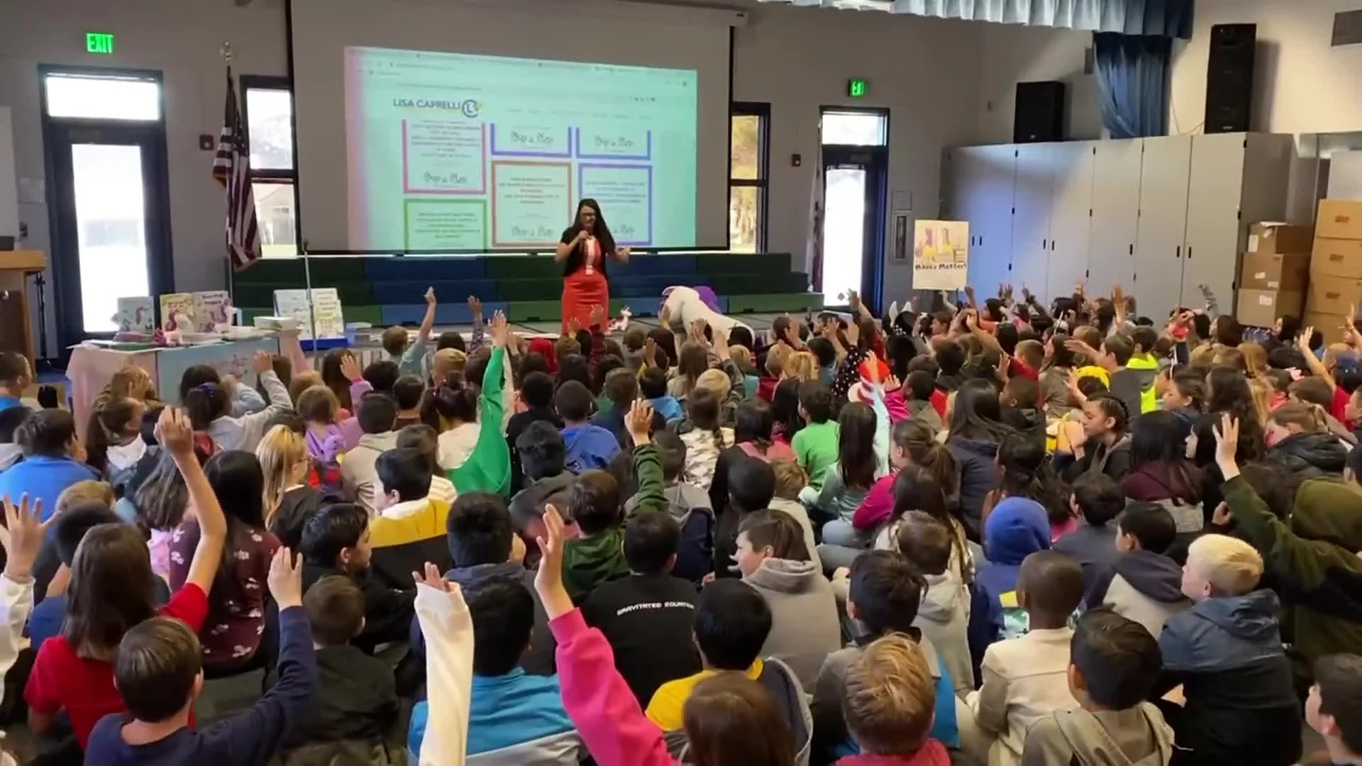 Lisa Caprelli speaking to elementary school students as children raise their hands