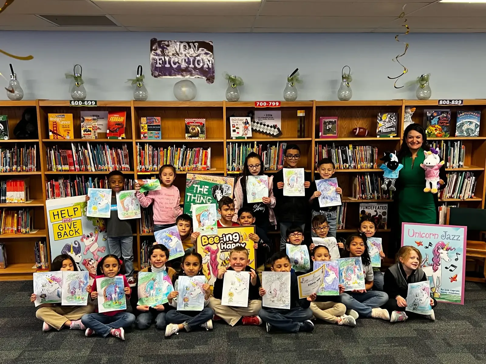 Lisa Caprelli with students displaying Unicorn Jazz artwork and books in their library