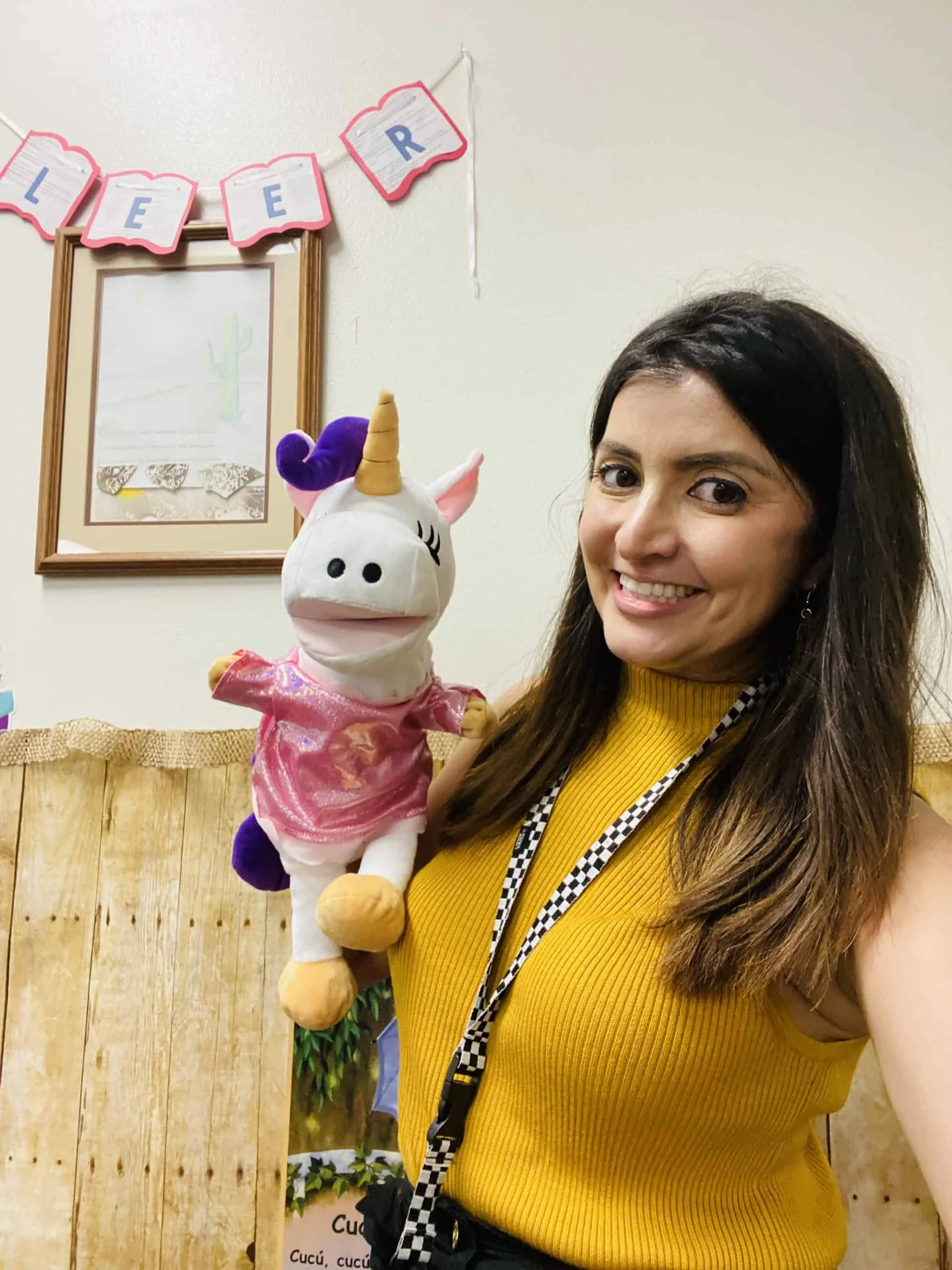 Woman holding a white unicorn puppet dressed in pink.