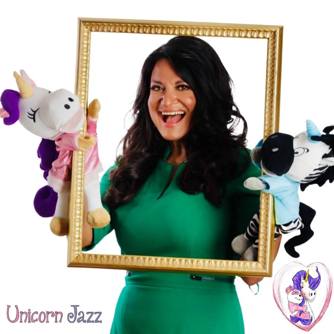 Lisa Caprelli holding a gold frame with Unicorn Jazz character puppets.