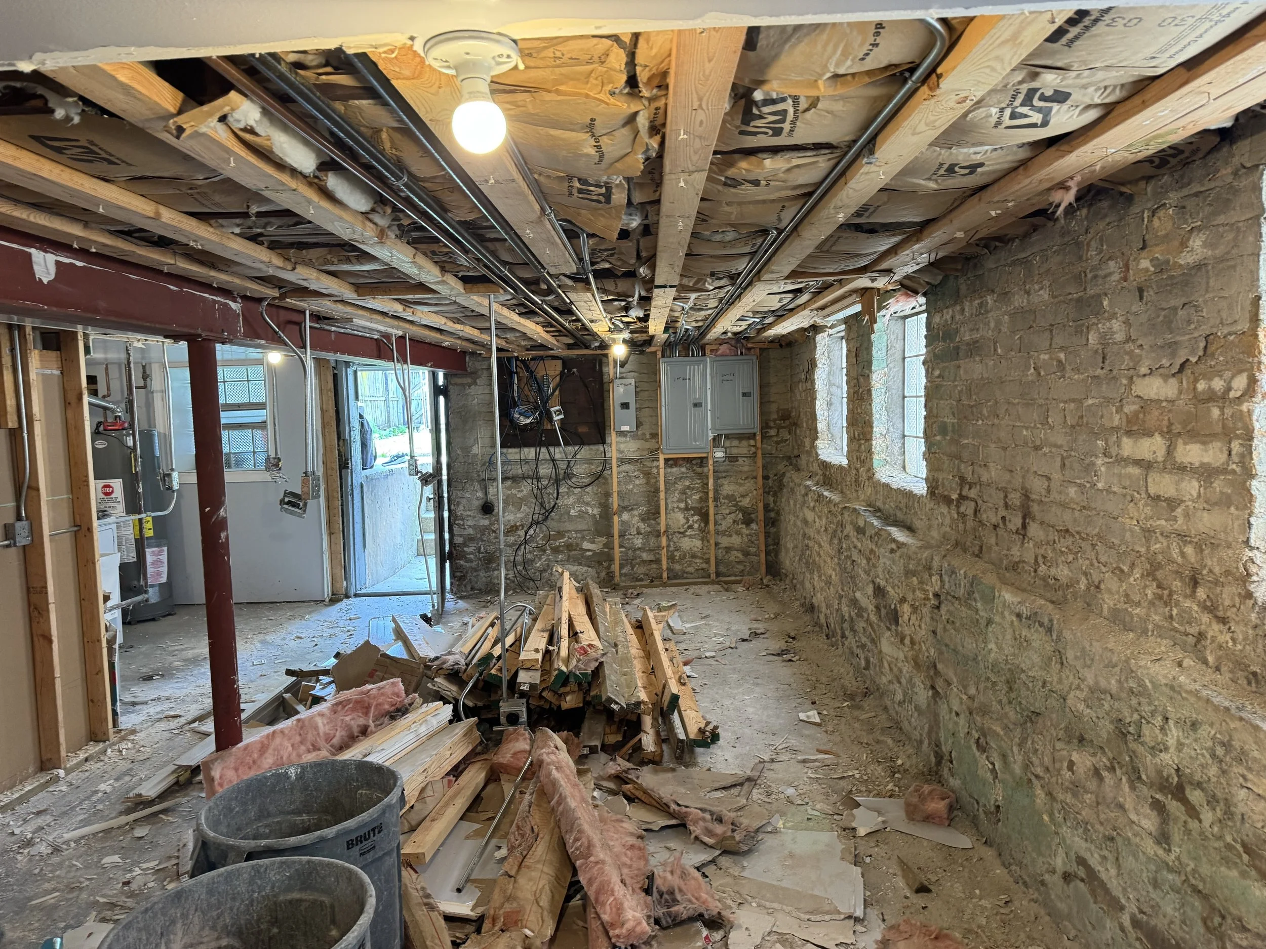 Demolition underway, framing lumber and insulation piled on the floor