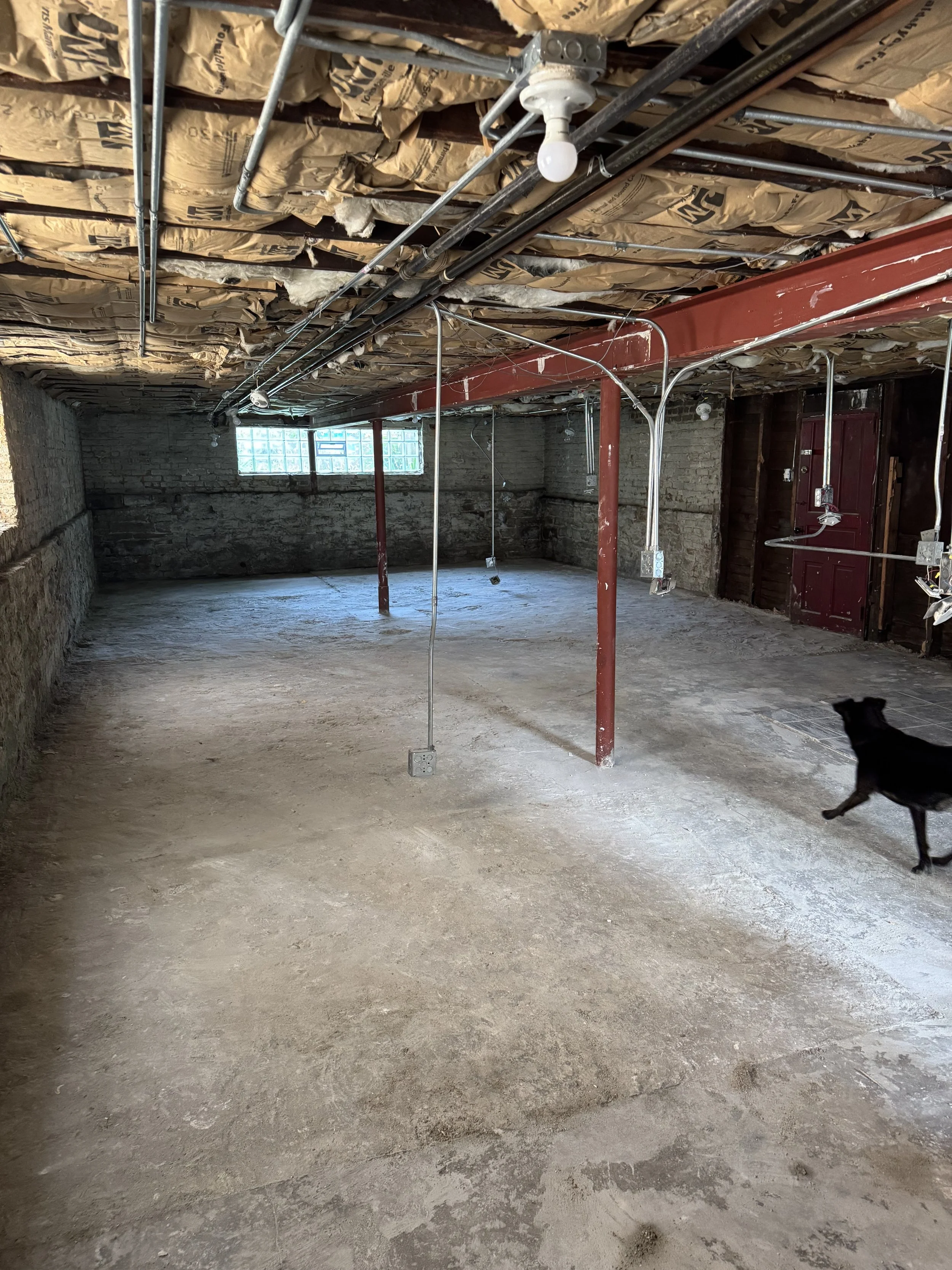 The gutted basement, bare stone walls and exposed joists overhead