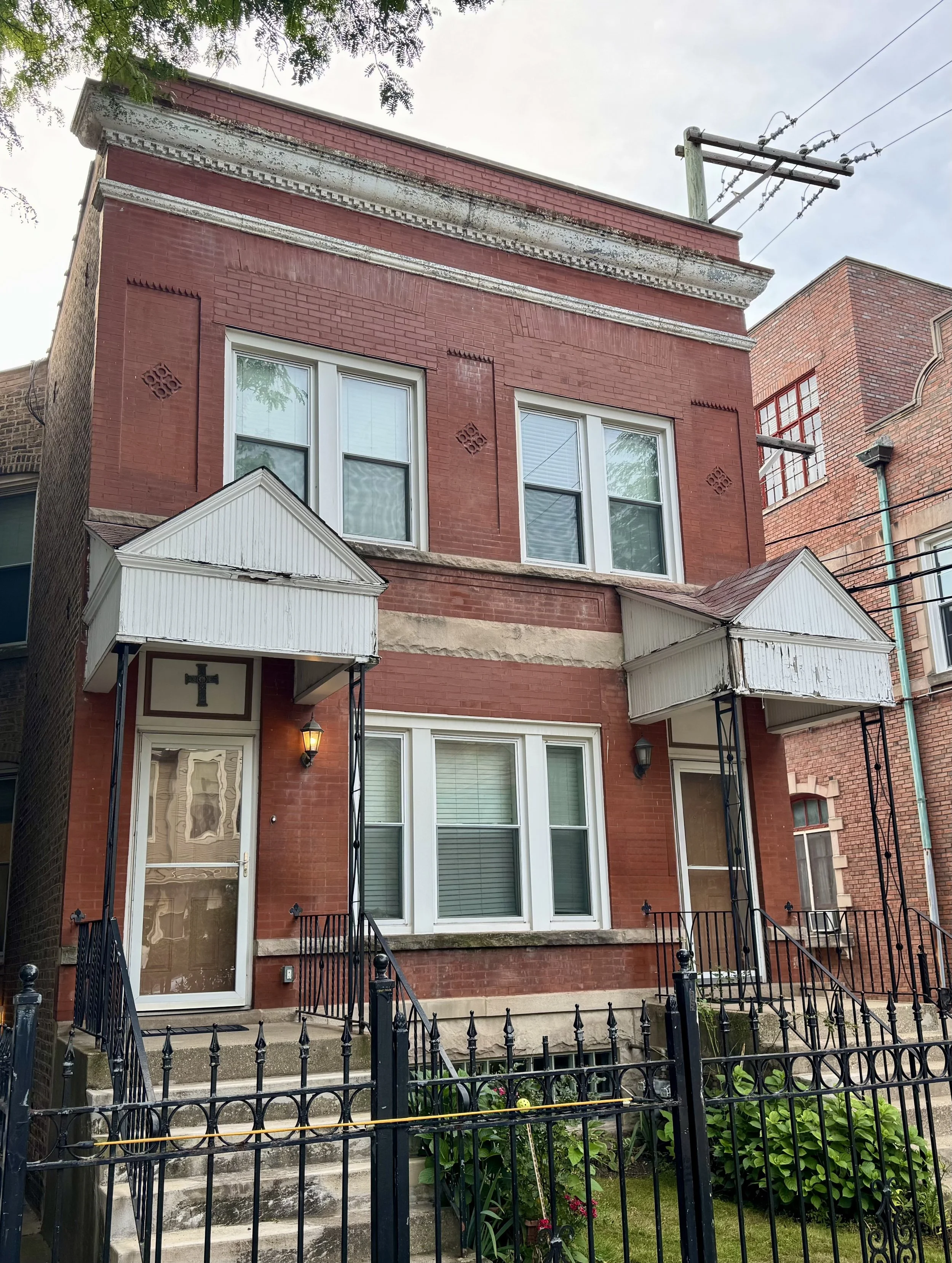 The two flat from the street: red brick, two front doors, iron fence
