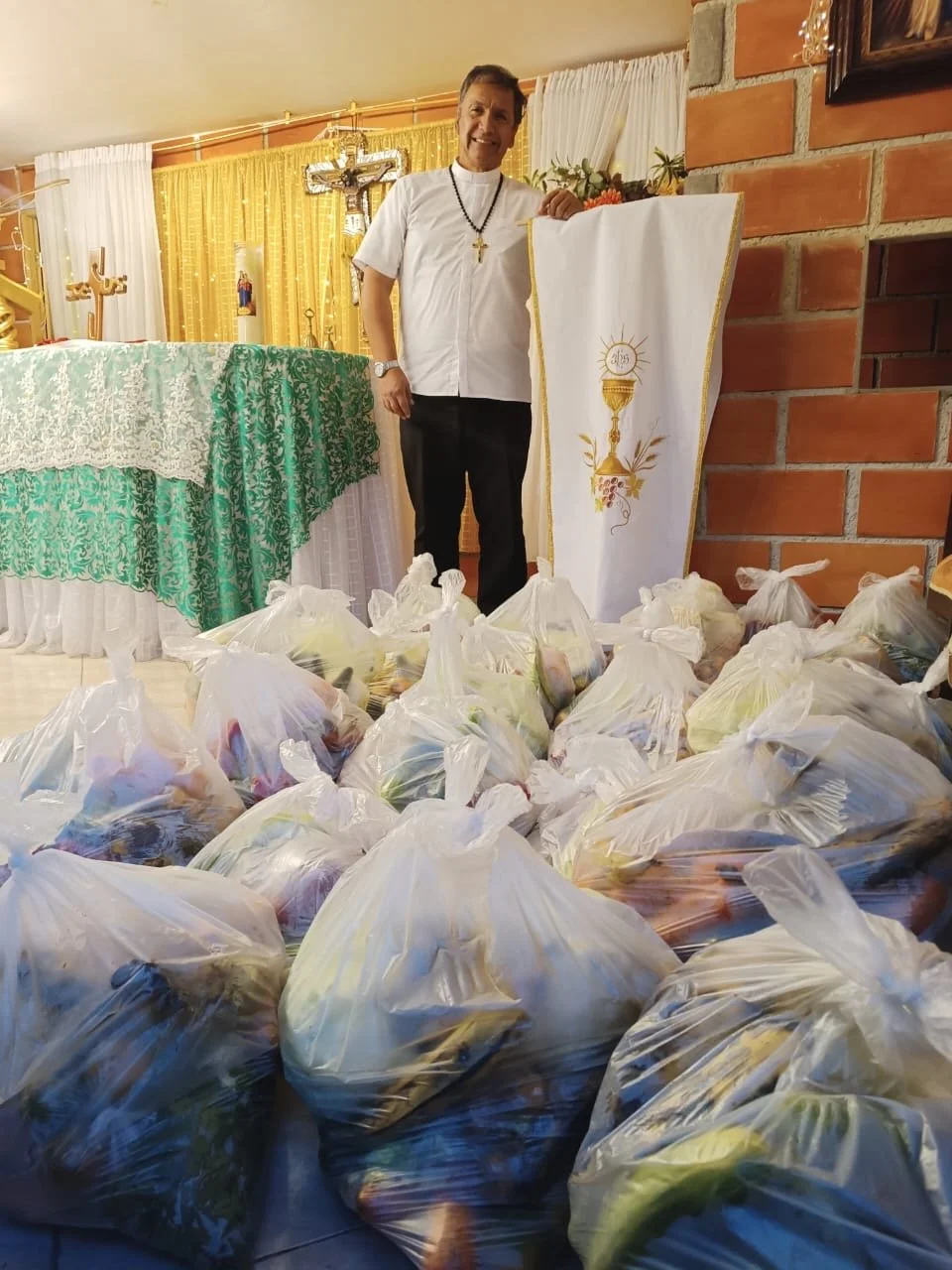 Padre Willman junto a bolsas de ayuda alimentaria