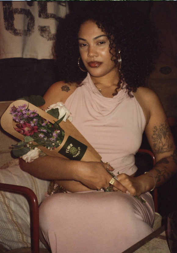 Guest holding a wrapped FLWR bouquet at an art event