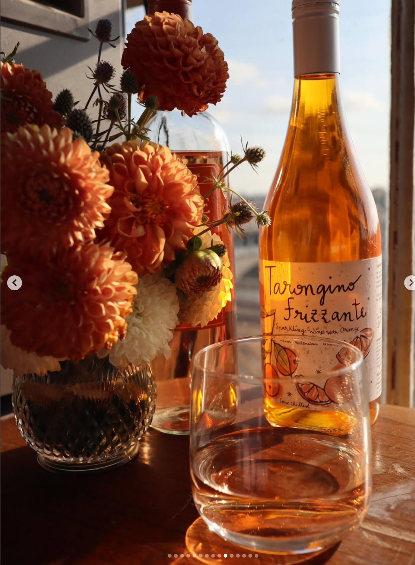 Orange floral arrangement with wine in warm light