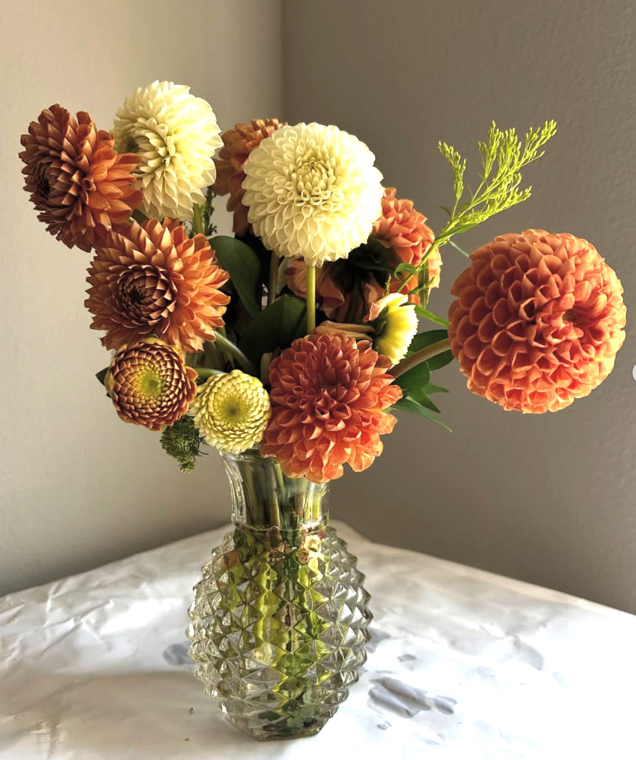 Orange and white dahlias in a crystal vase