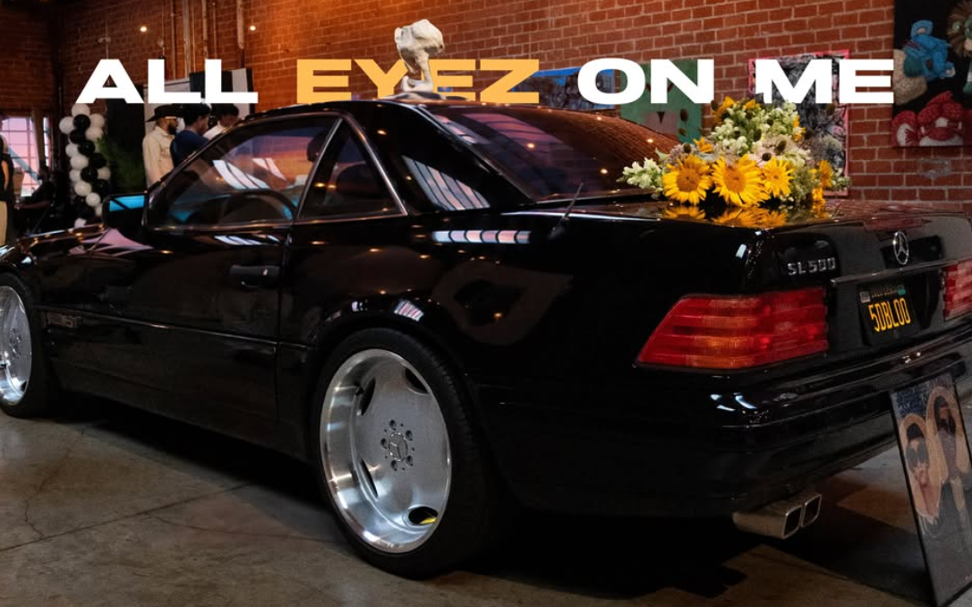 Black Mercedes with a yellow floral installation beneath gallery artwork
