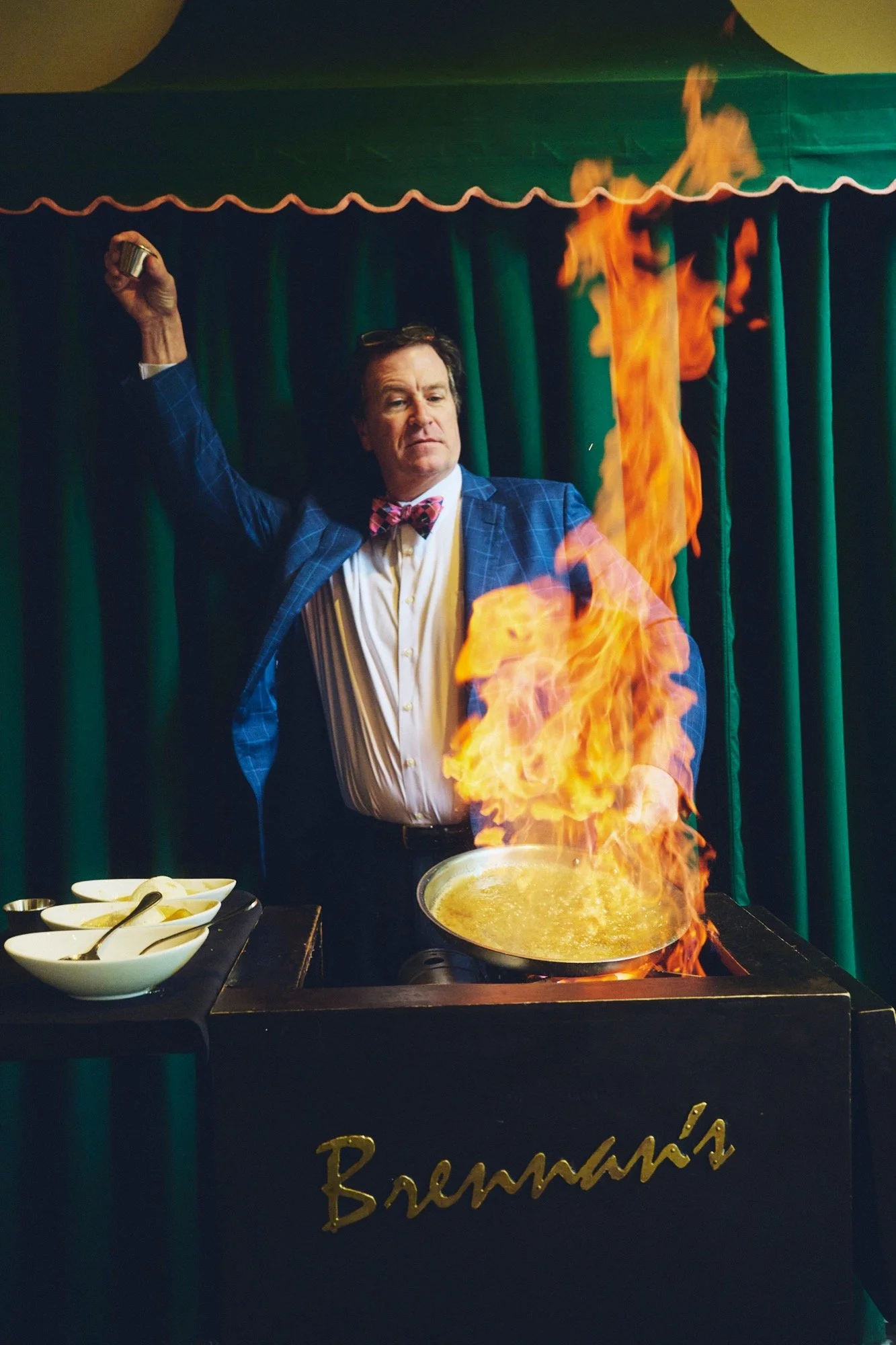 A Brennan’s server preparing Bananas Foster over a tall tableside flame