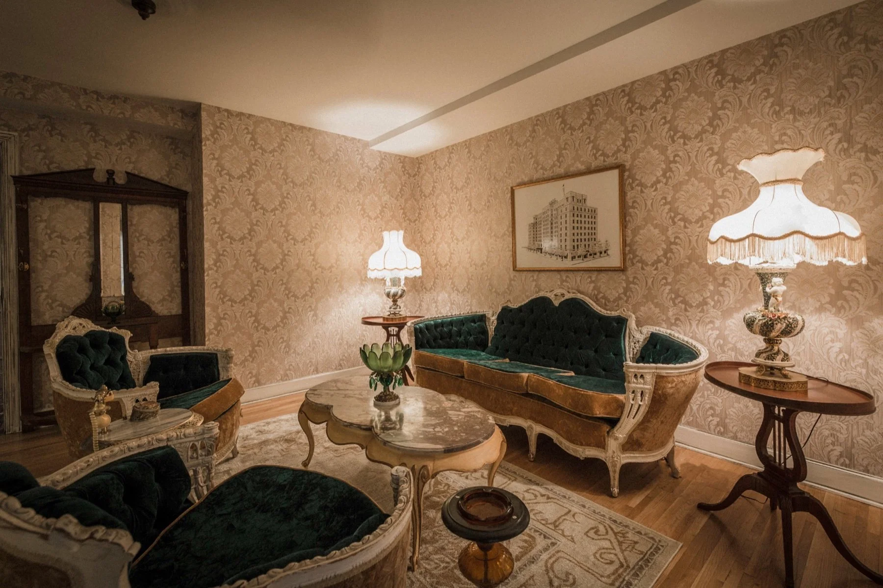 Period seating, patterned wallpaper, and lamps in the sitting room of Room 311