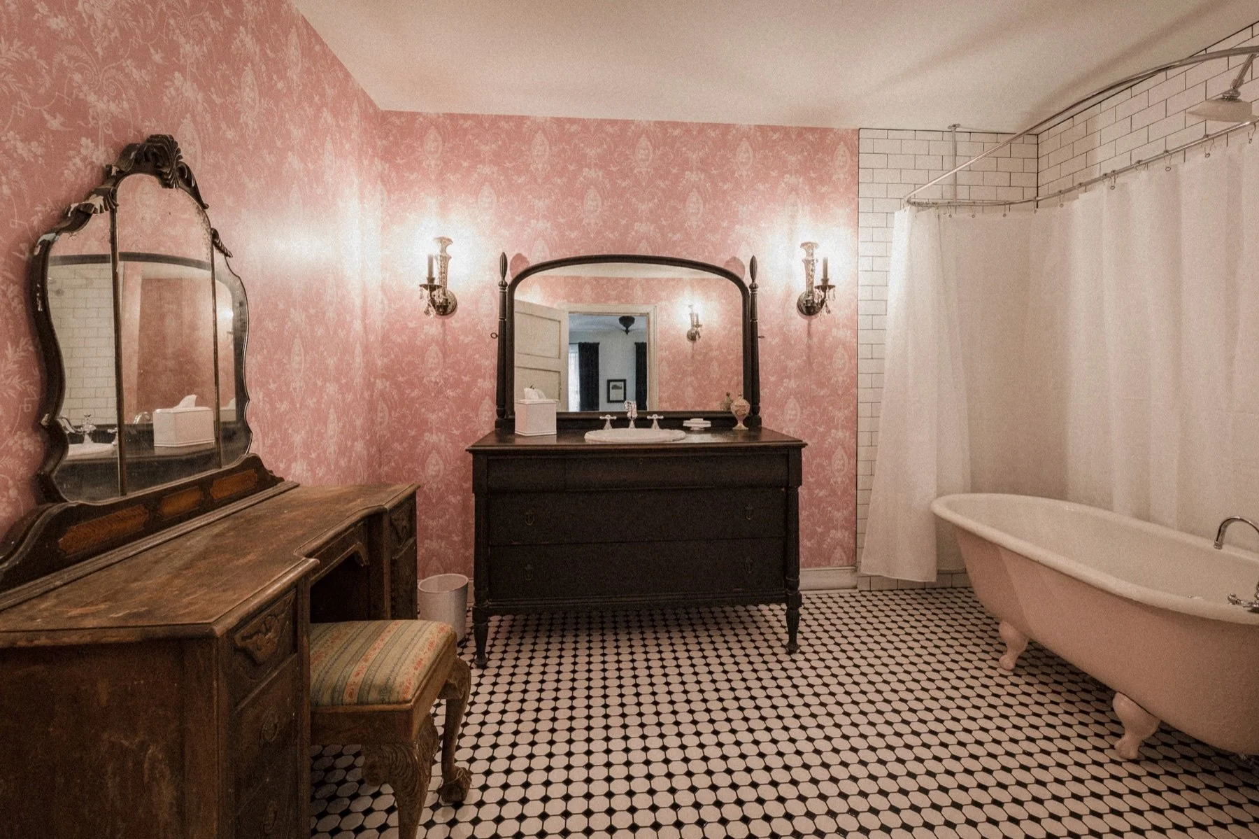 The bathroom in Room 311, with pink patterned walls, a clawfoot tub, and period fixtures