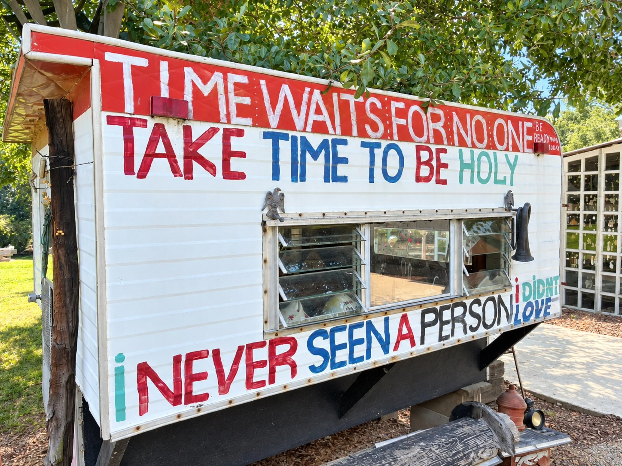 A hand-painted Paradise Garden sign reading Time waits for no one and Take time to be holy