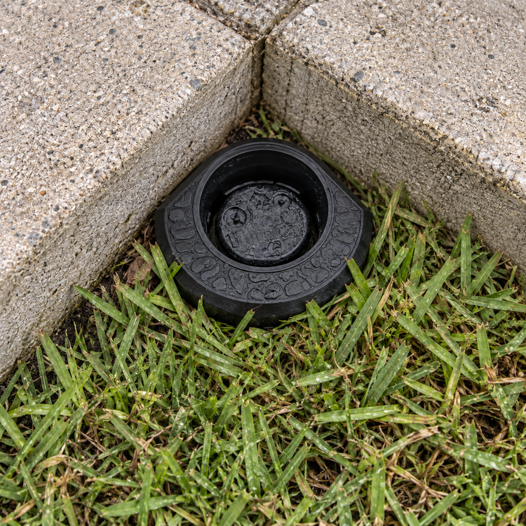 Illustration of a black Corner Guard around a sprinkler head at a concrete border corner.
