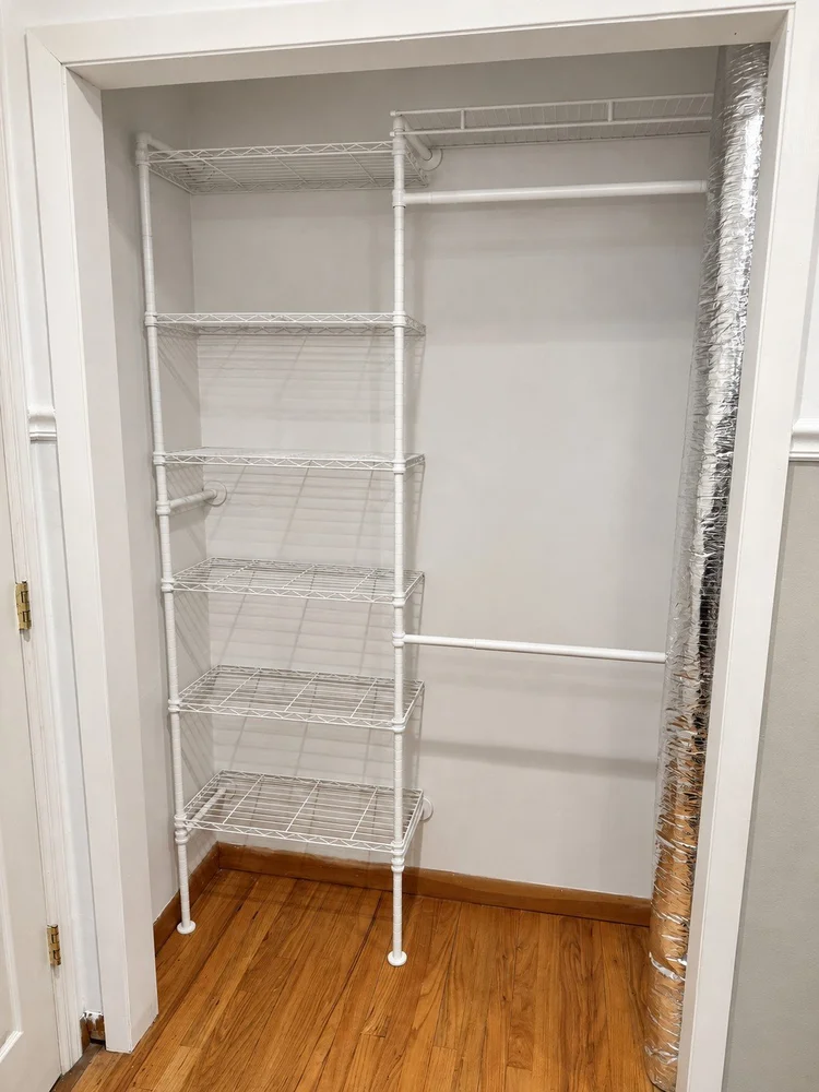 Exposed silver air-conditioning duct beside the original white closet shelving.