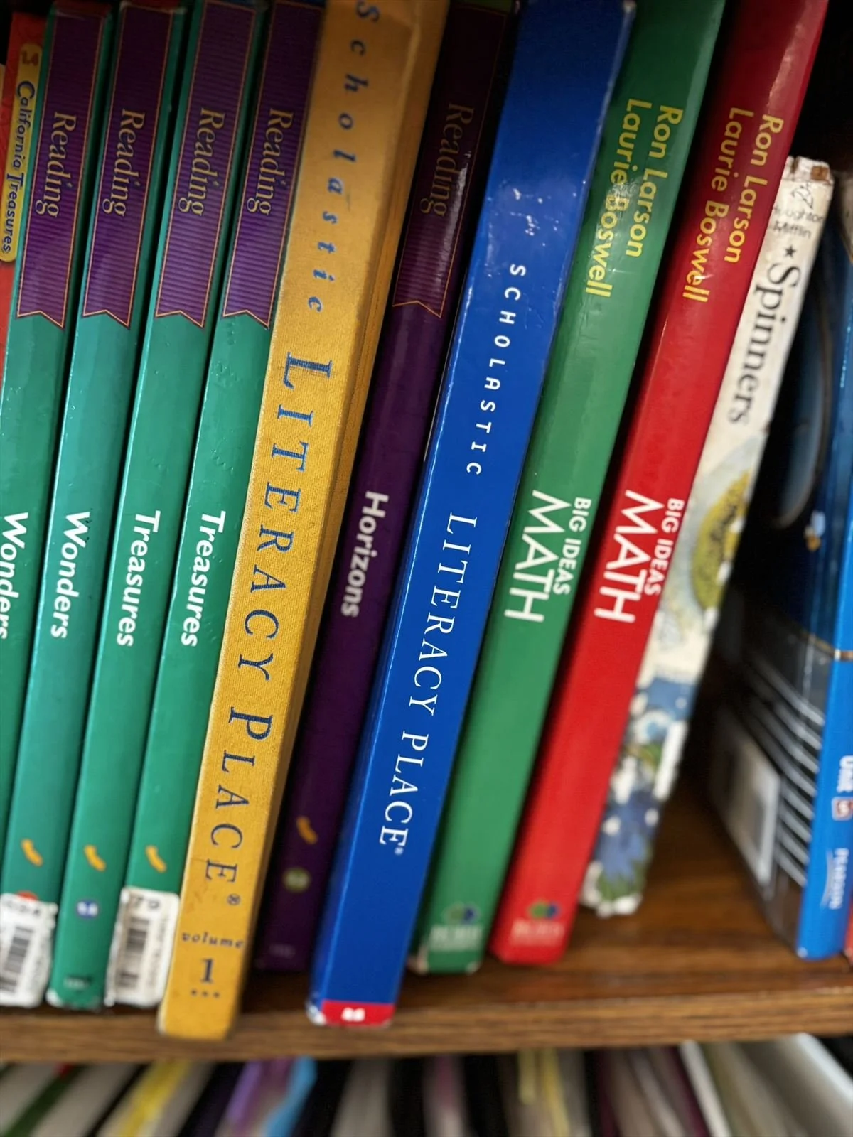 Reading and math curriculum on the classroom shelf, including Scholastic Literacy Place, Reading Wonders and Big Ideas Math