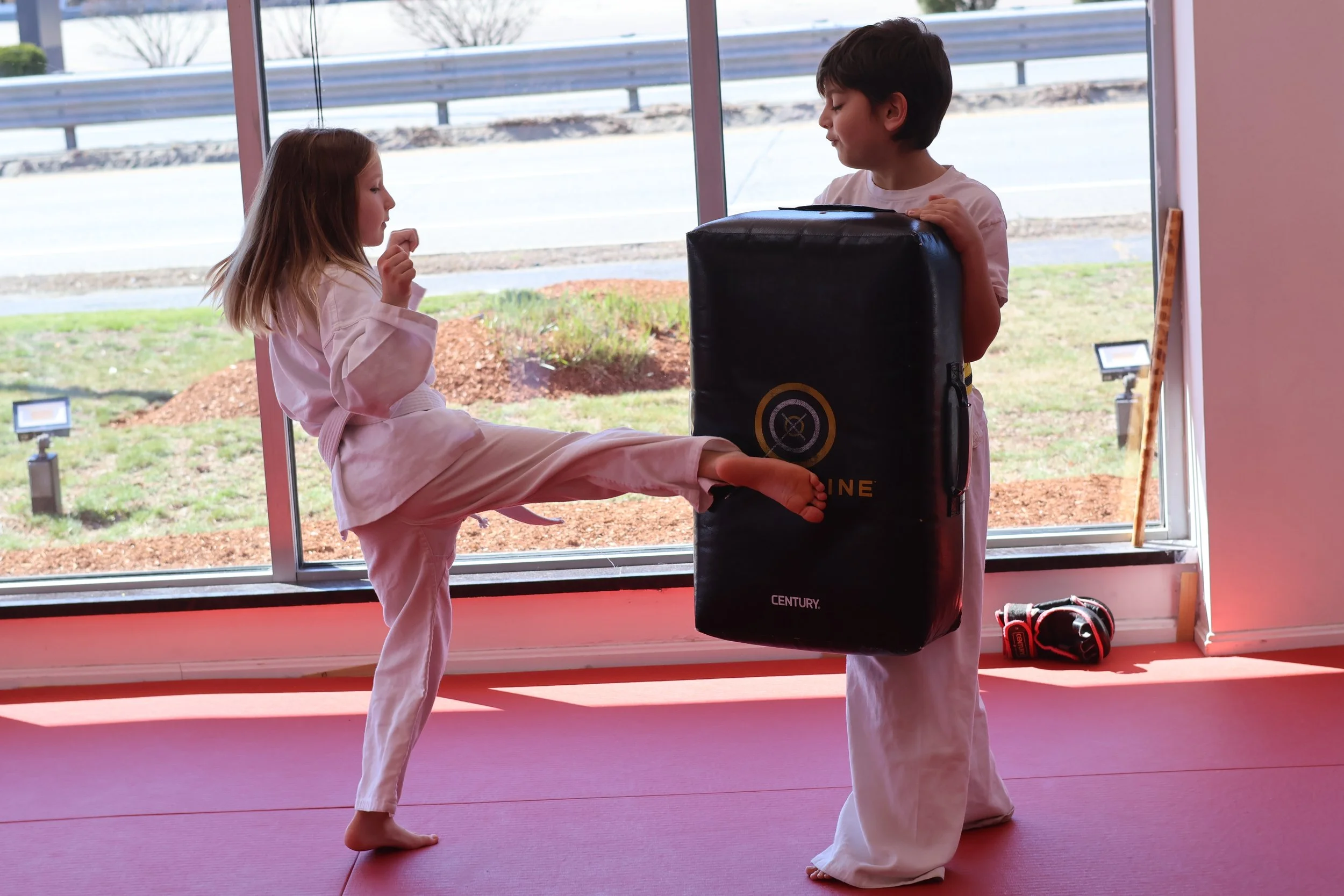 A Little Ninjas student practicing a kick against a training pad