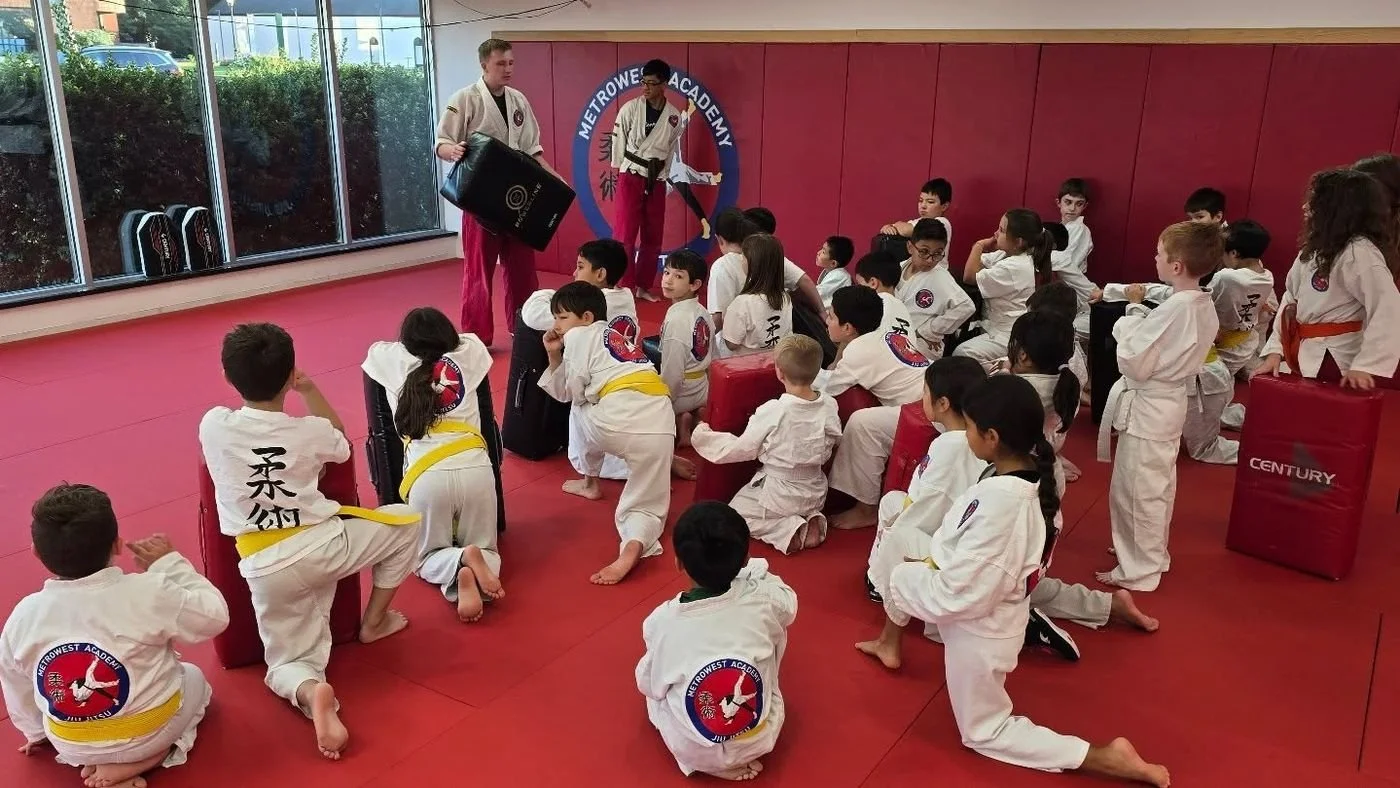 A coach holding a training pad while the Kids class listens