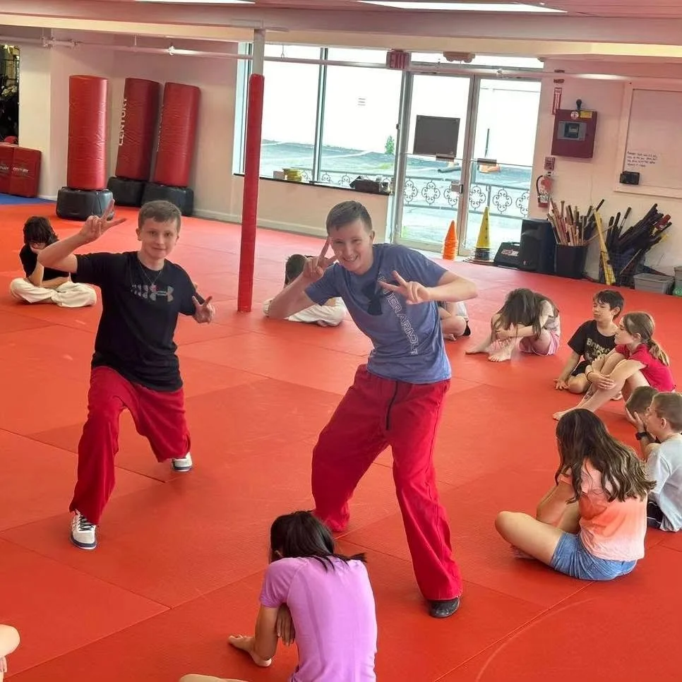 Students enjoying a playful moment together on the Academy mat