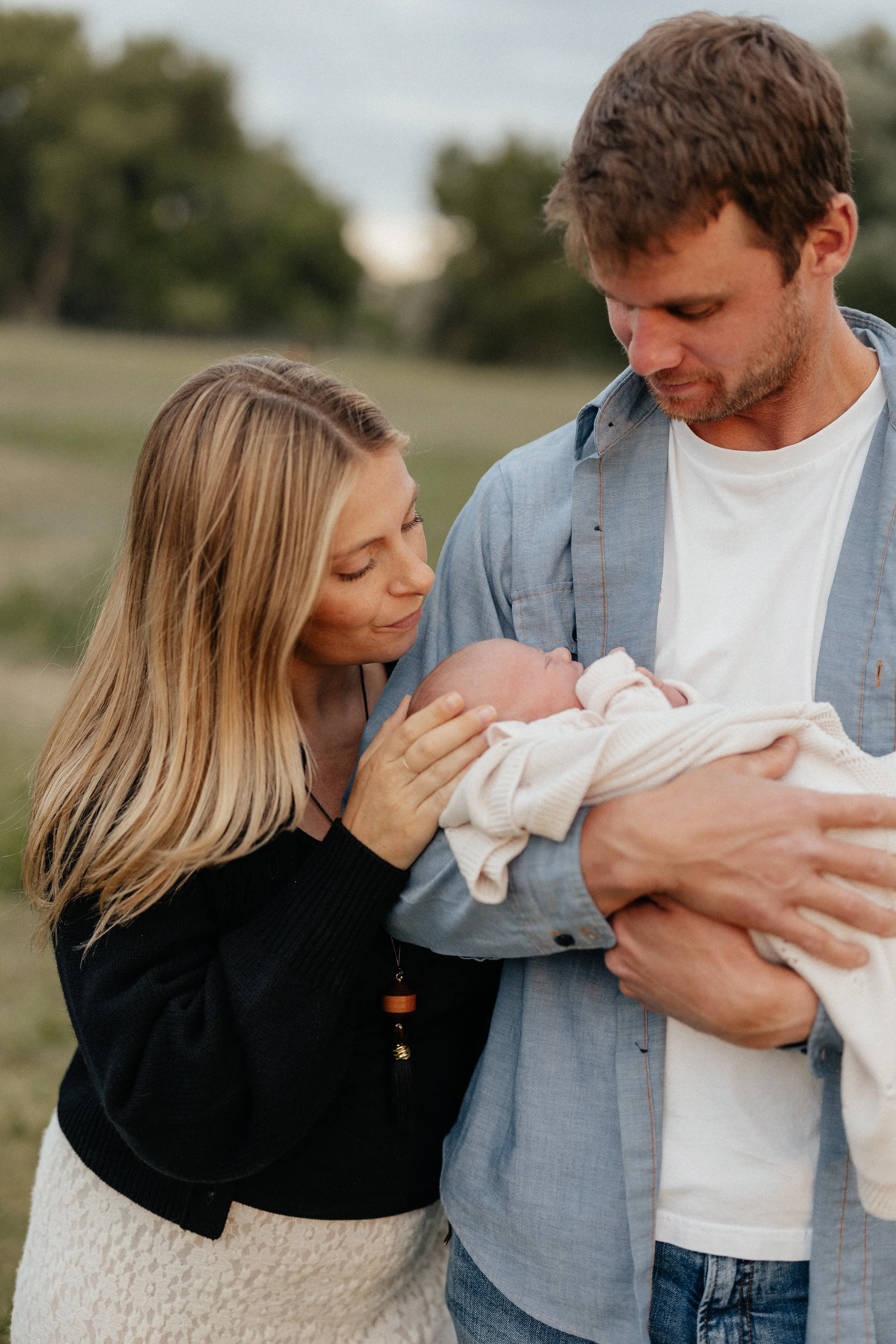 Parents holding their newborn in the pasture