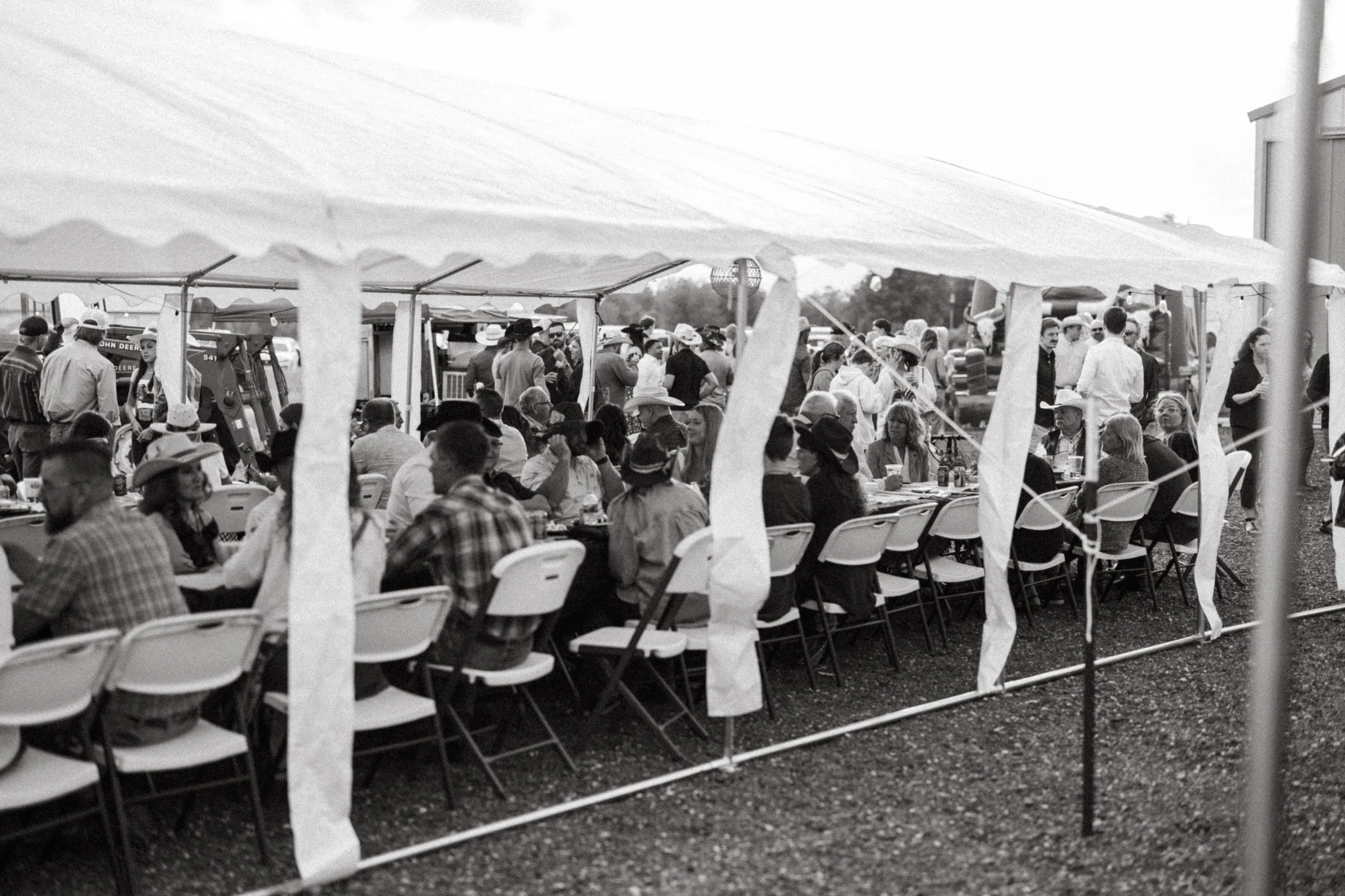 Guests gathered at tables beneath the celebration tent in black and white
