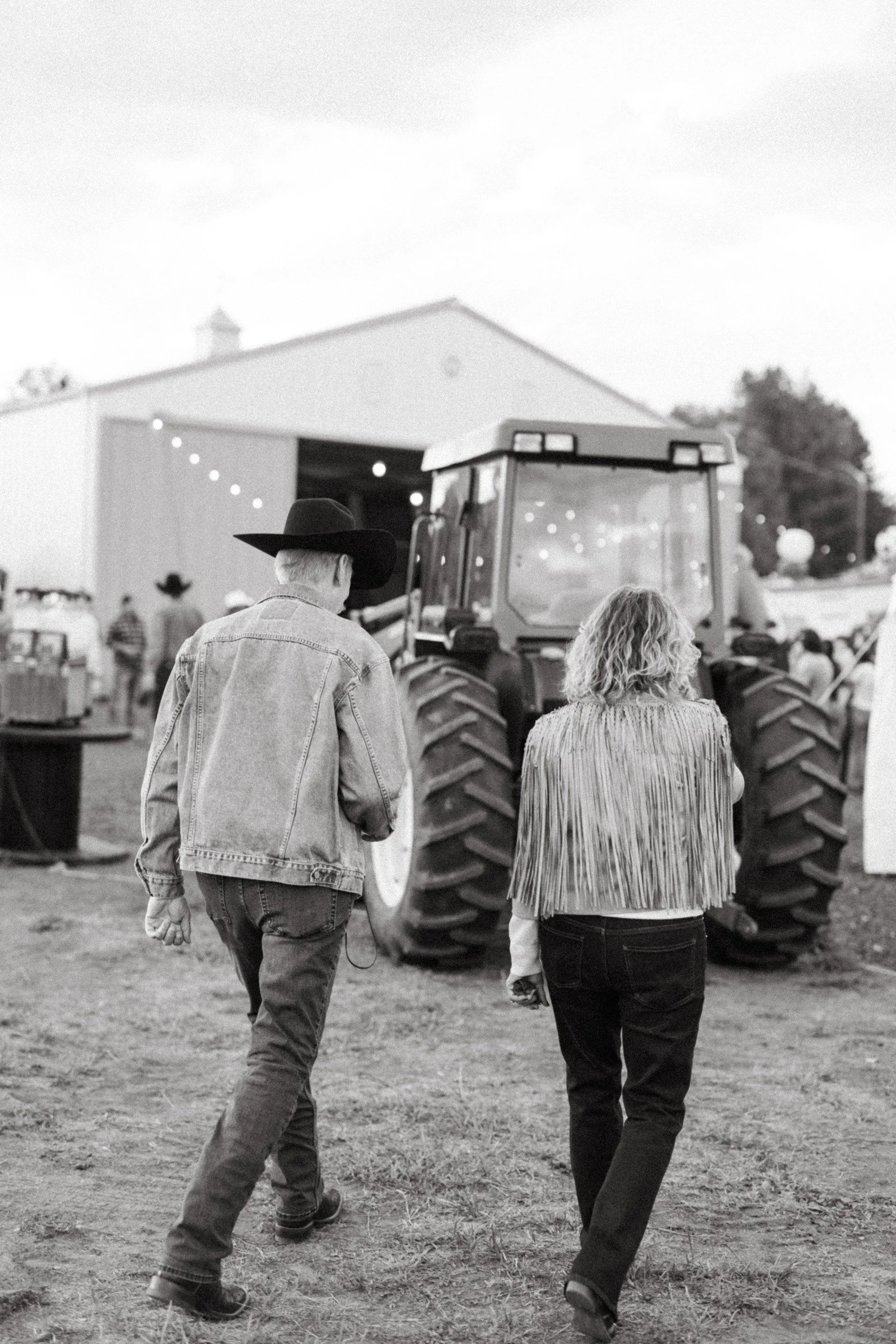 Two guests walking past a tractor toward the gathering barn