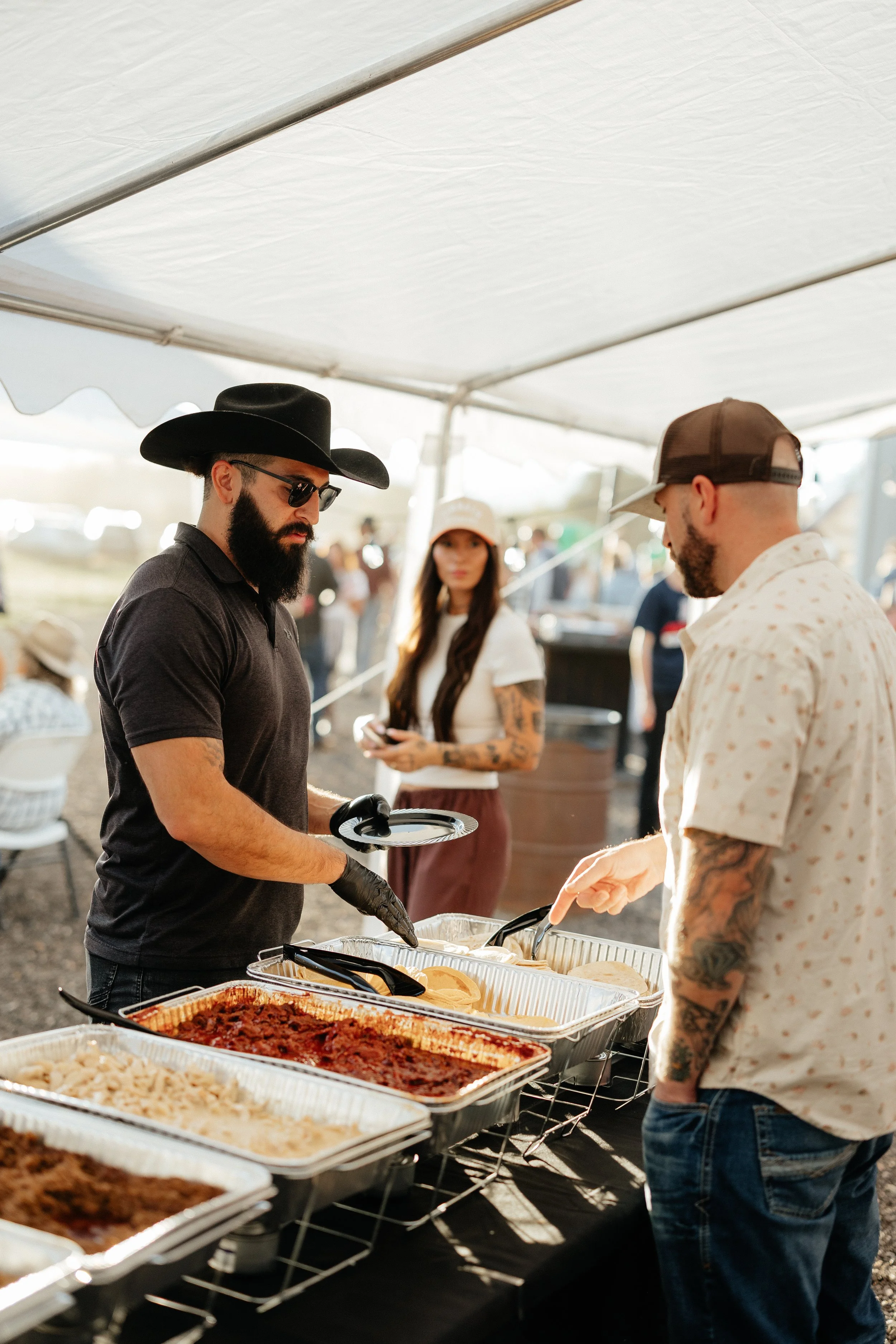 Guests serving a farm dinner buffet beneath the tent