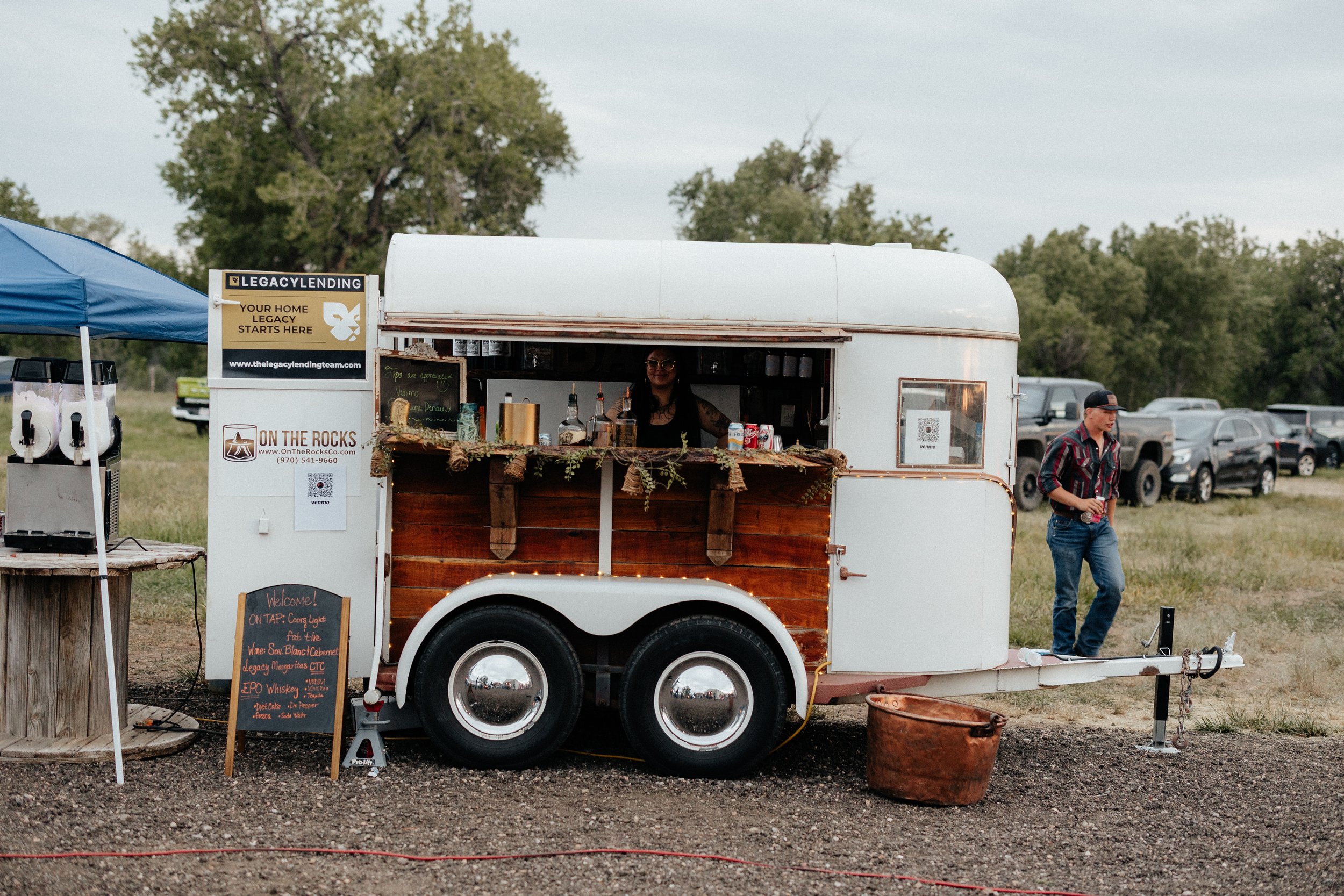 A vintage horse trailer serving drinks at a farm celebration