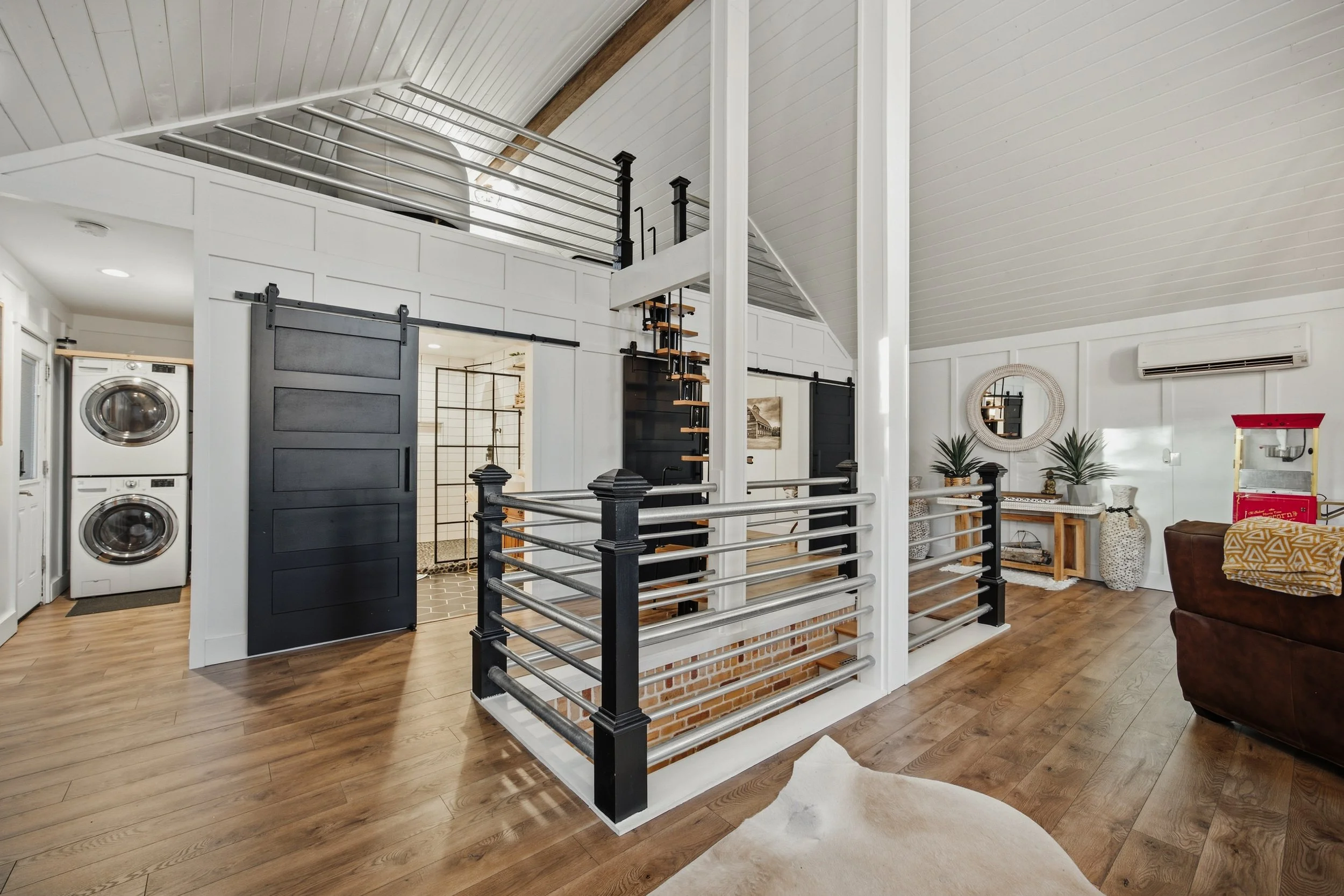 Loft overview showing laundry nook, bathroom, railing and upper sleeping loft