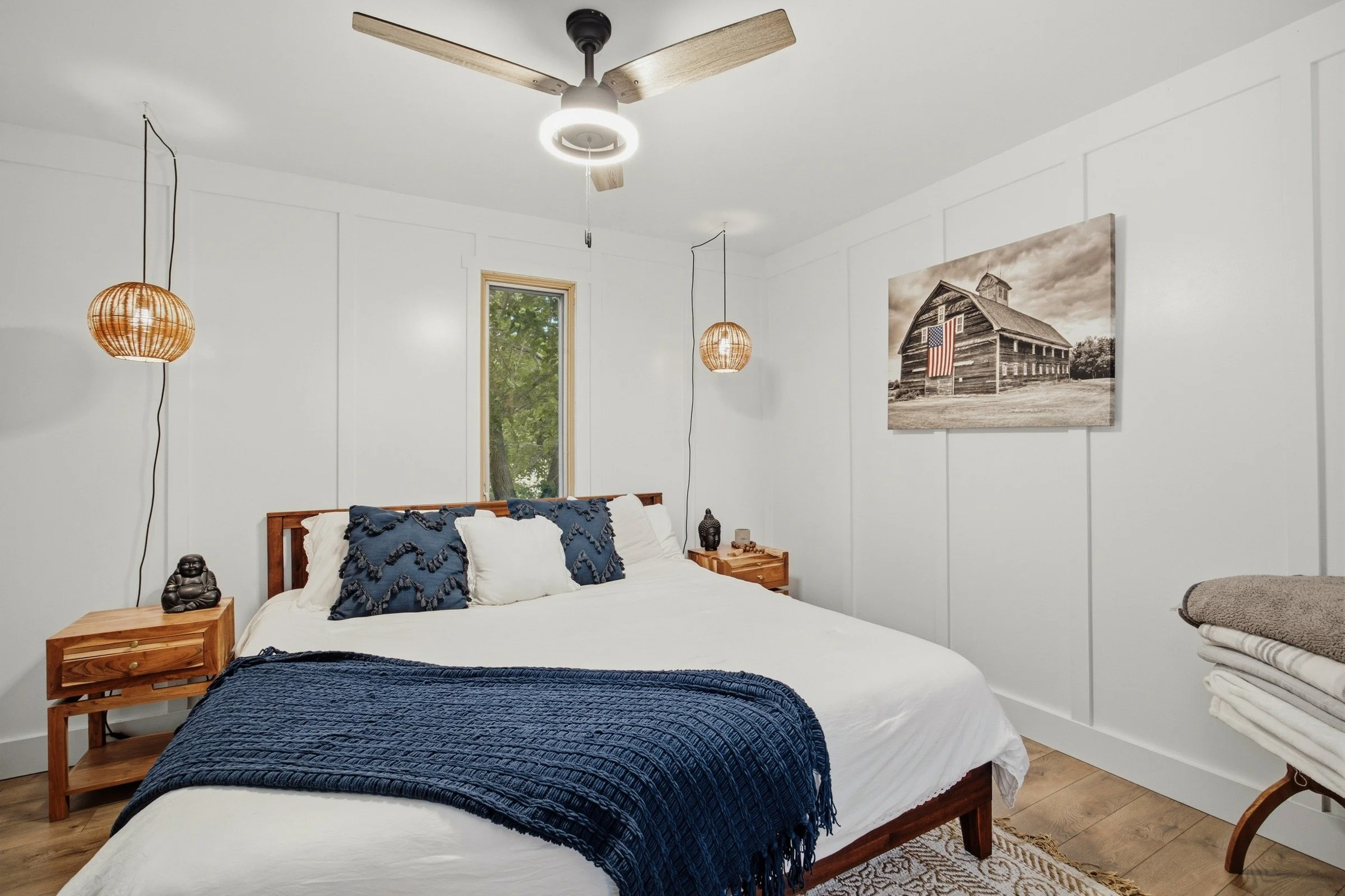 Main bedroom with white bedding, navy accents and warm wood furniture