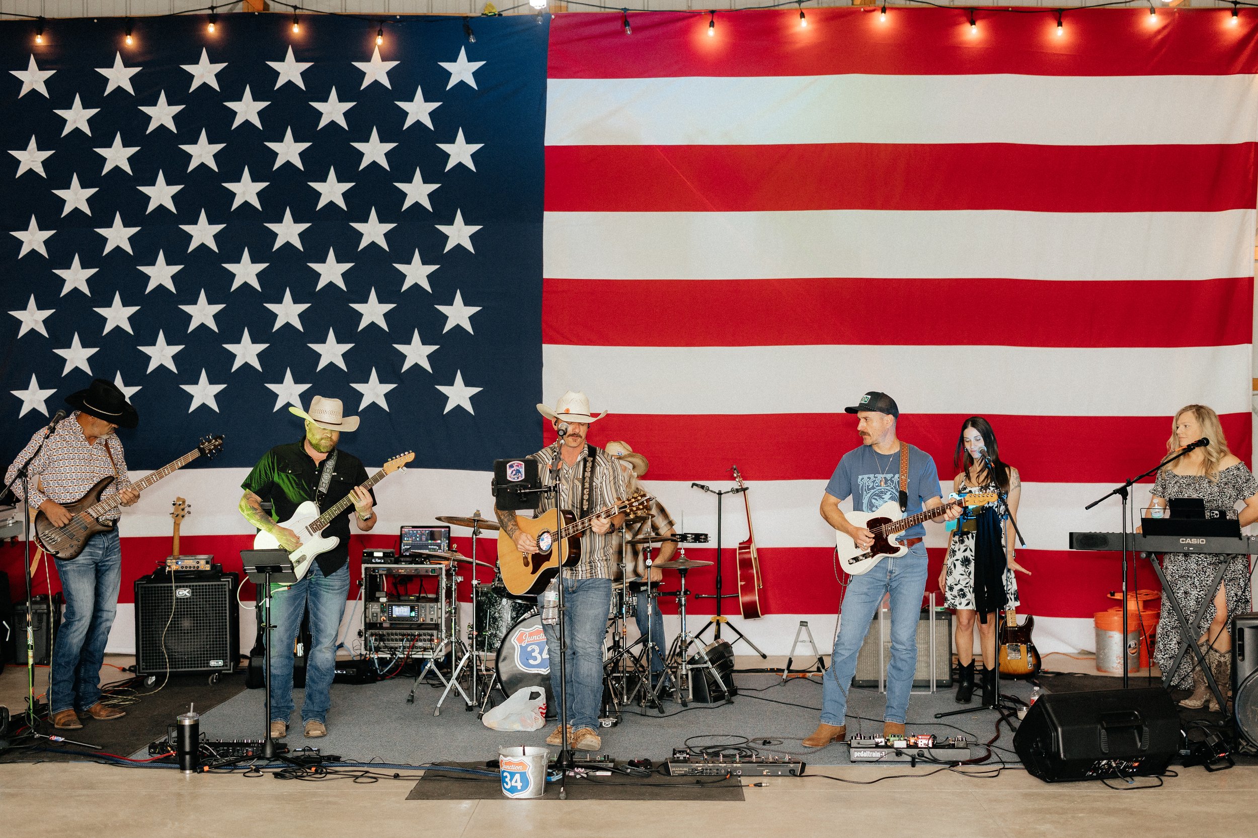 A live band performing together beneath the large American flag