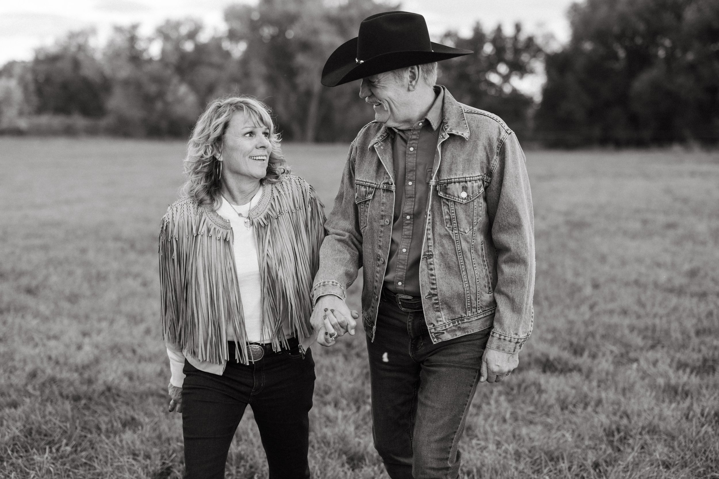 Black-and-white portrait of a couple holding hands in the pasture