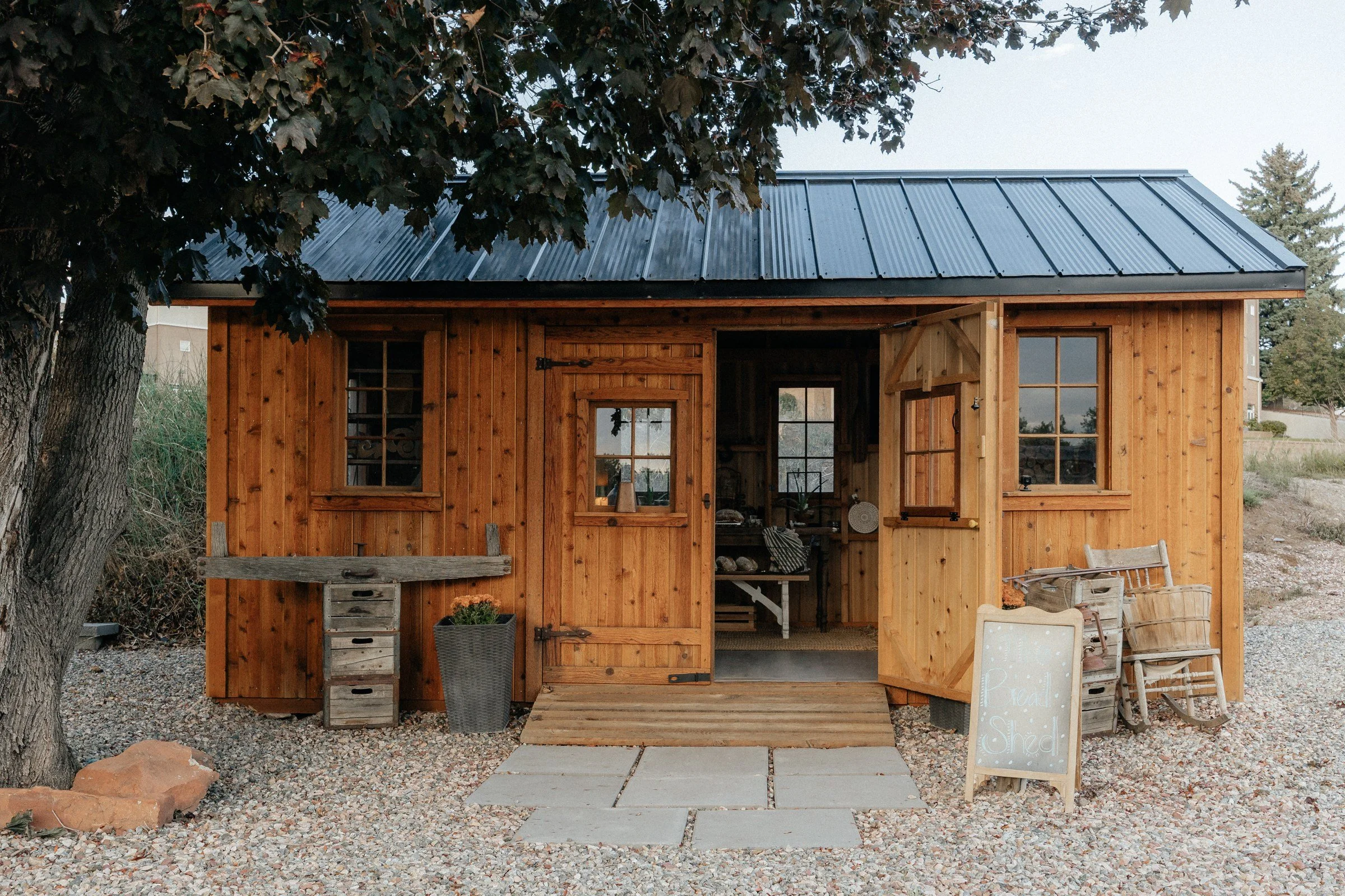 The wooden Lucks Farm Stand farm stand beneath mature trees