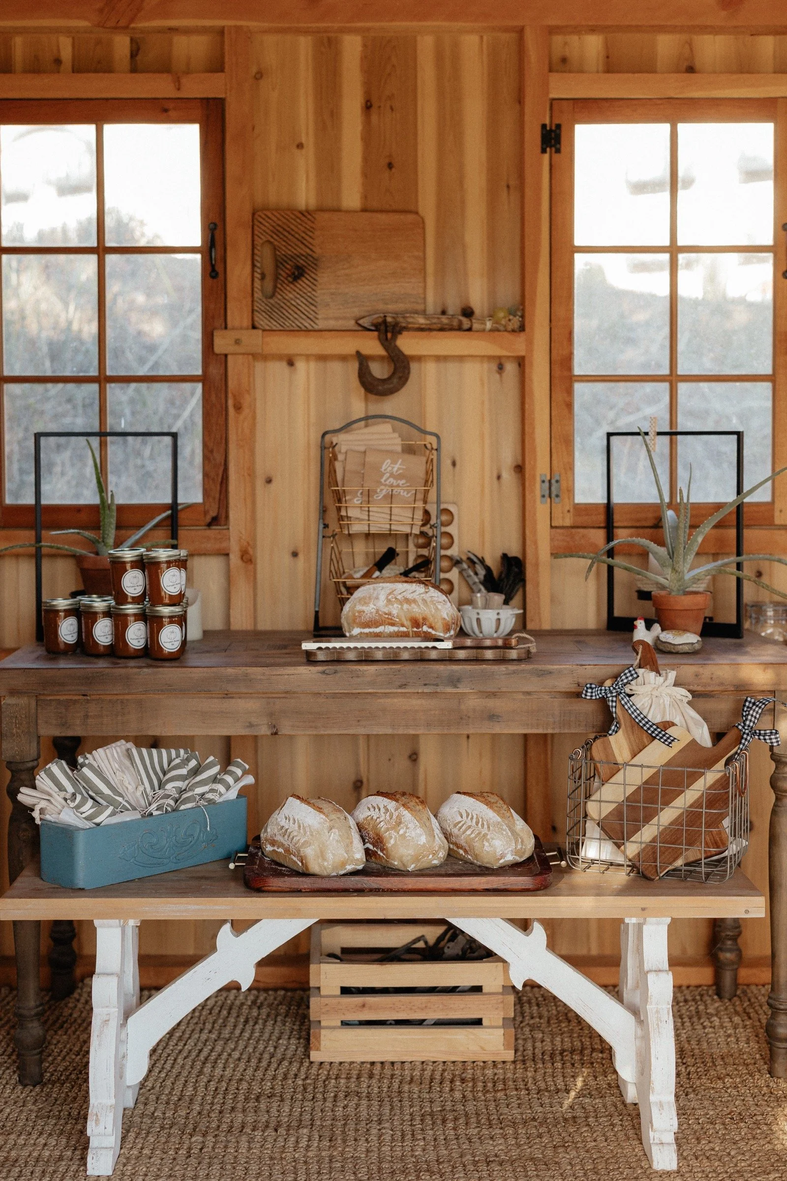 Lucks Farm Stand display with sourdough loaves, preserves and handcrafted goods between wooden windows