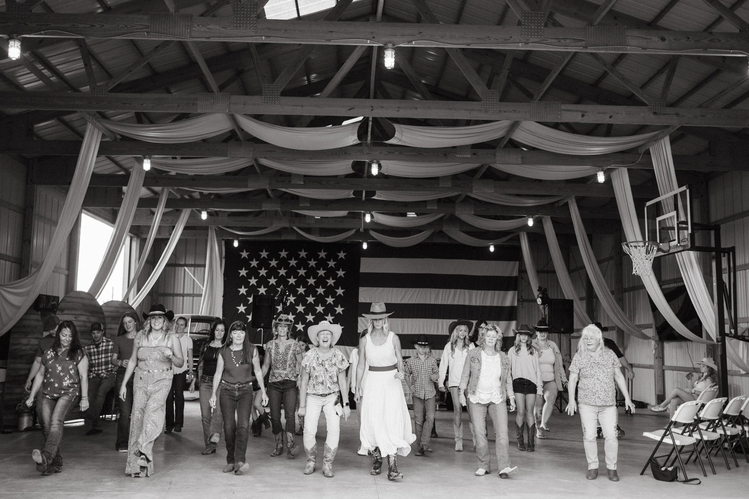 Guests line dancing beneath the draped beams in the barn at Legacy Family Night
