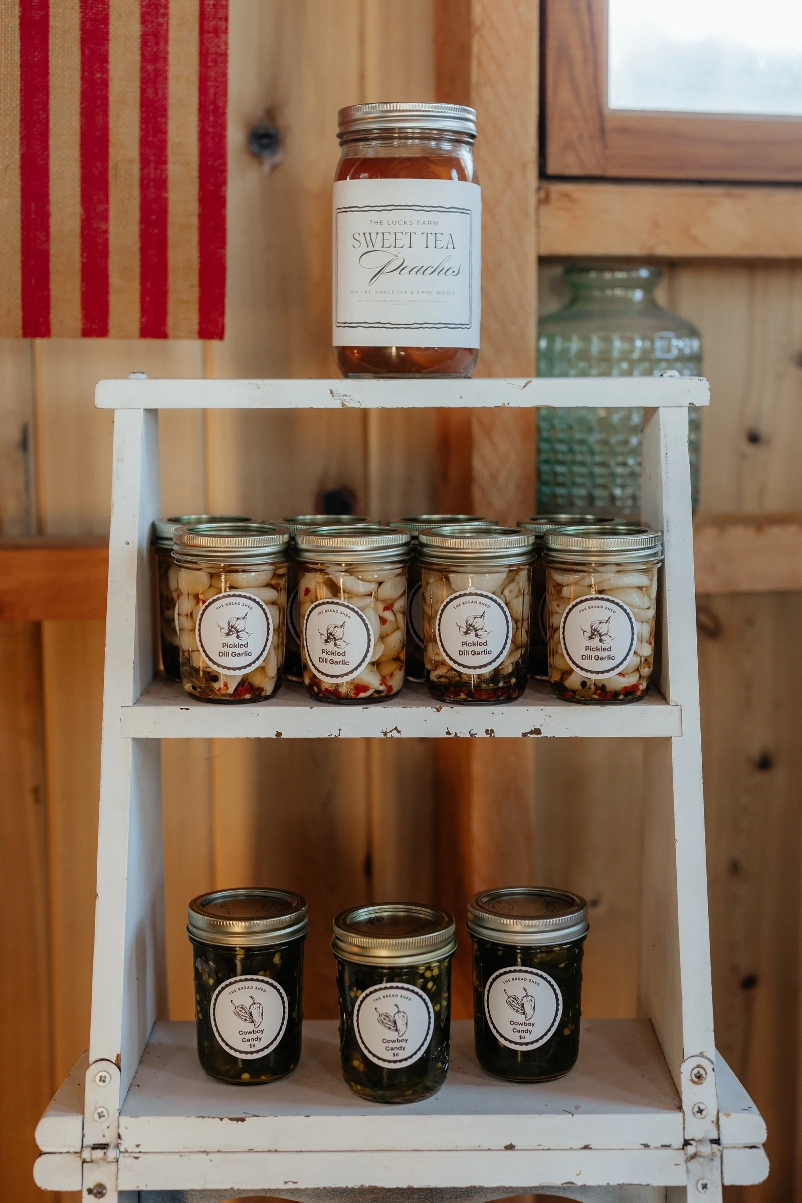 Pickled dill garlic and cowboy candy jars on Lucks Farm Stand shelves
