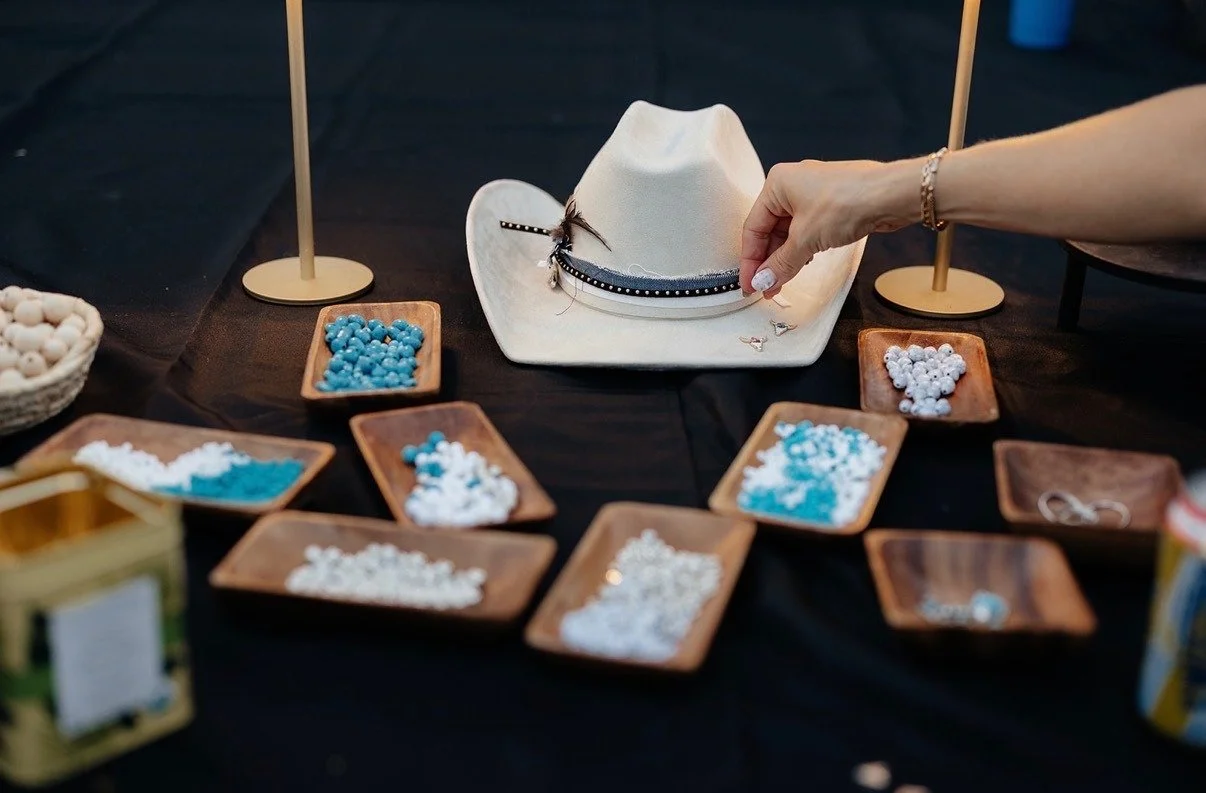 A white cowboy hat being decorated with beads and ribbon