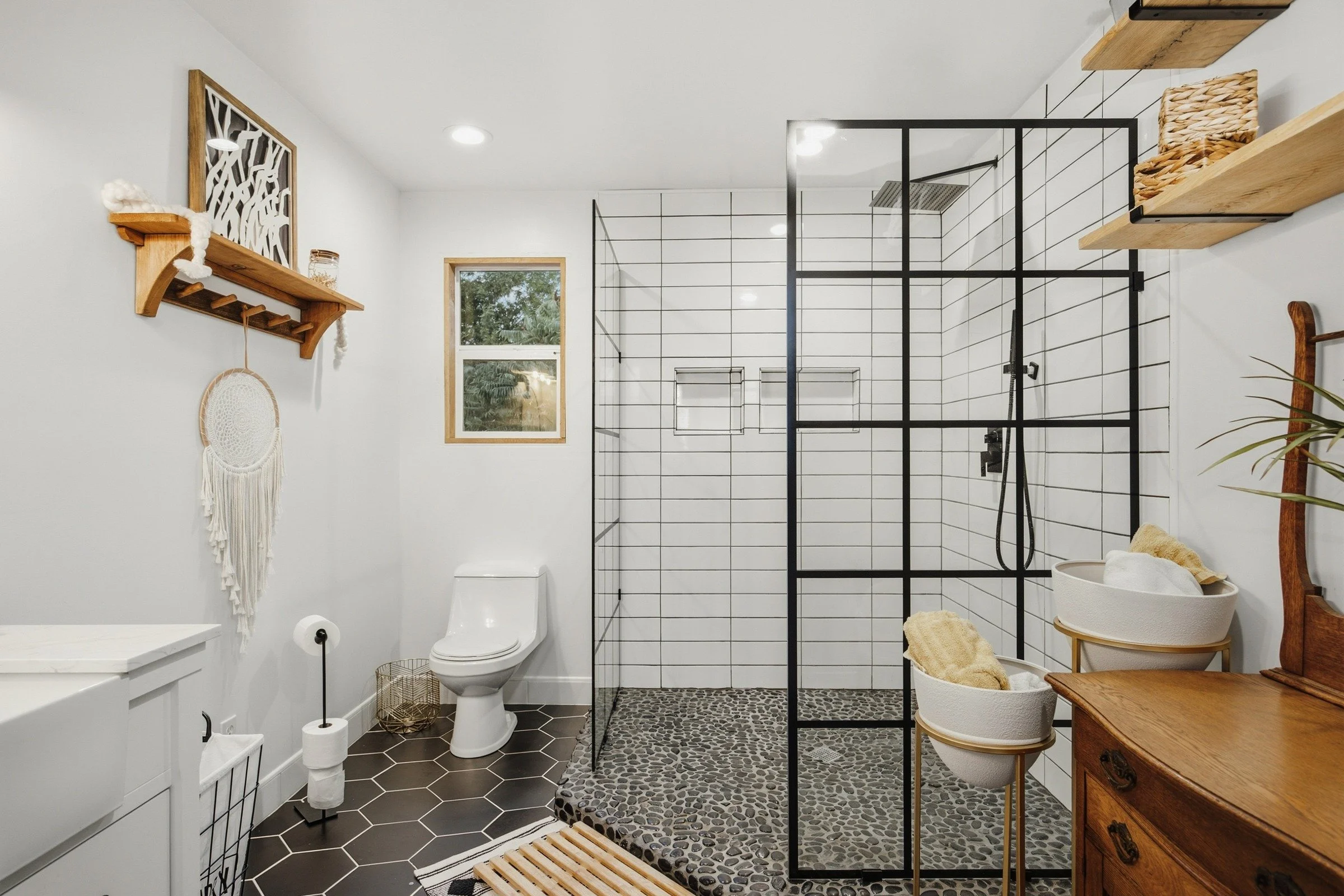 Full bathroom with black framed walk-in shower and pebble floor