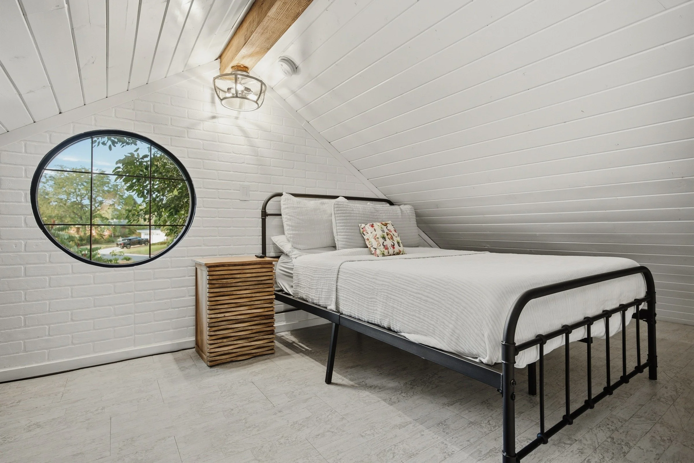 Upper sleeping loft with iron bed and circular window
