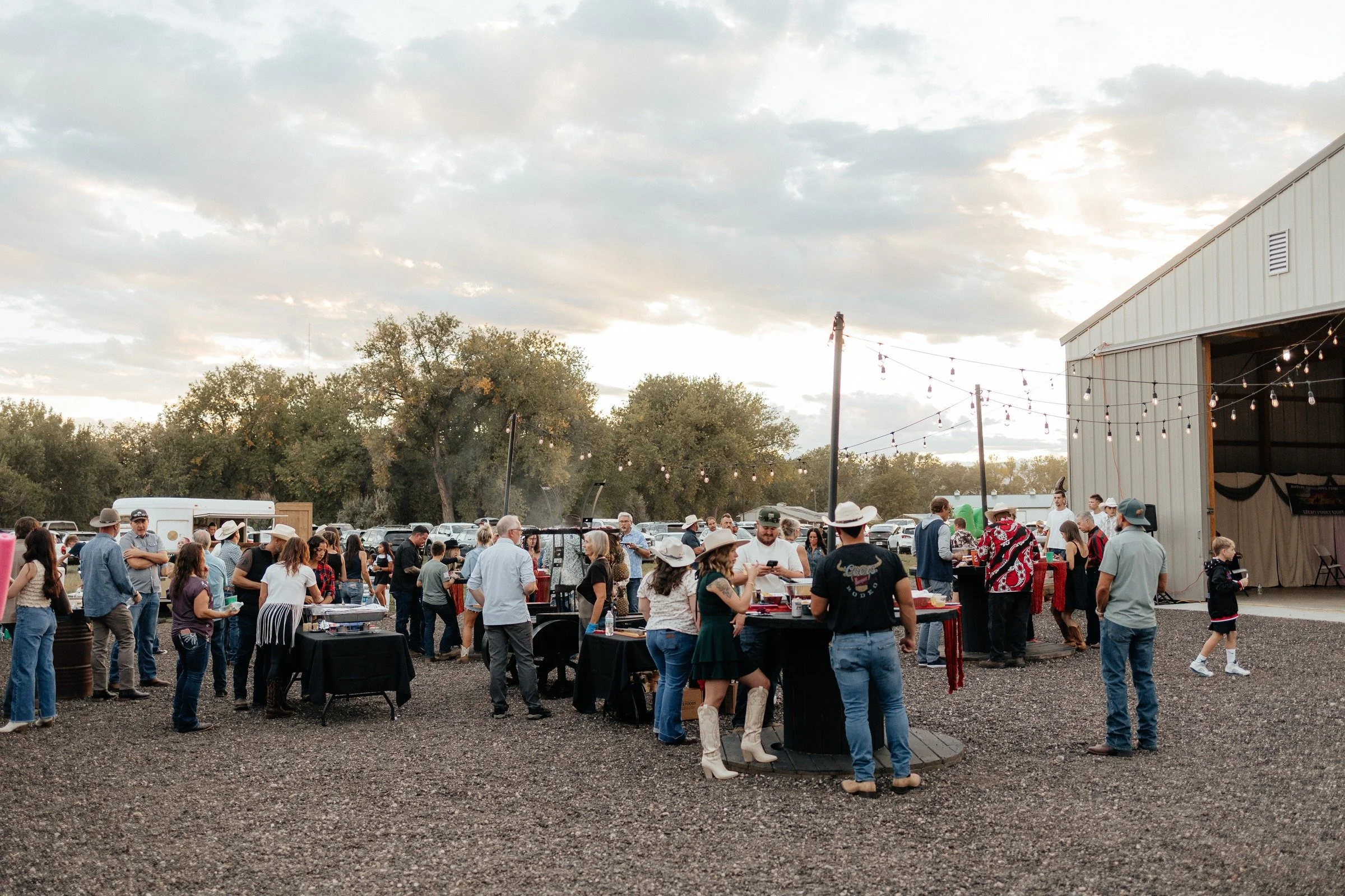 Guests gathered outside the barn under string lights at Legacy Family Night
