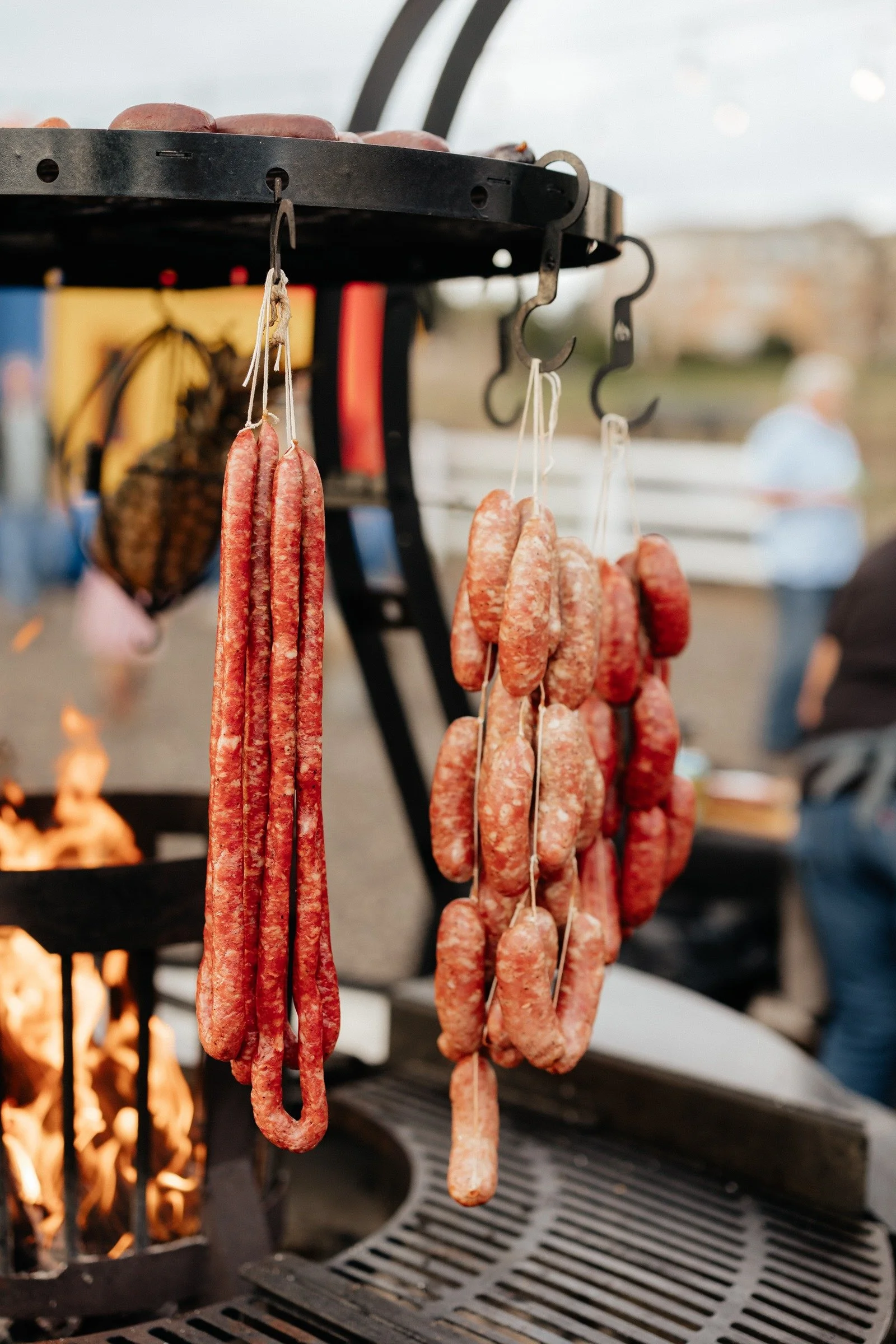 Sausages hanging over the flames of the outdoor wood-fired grill