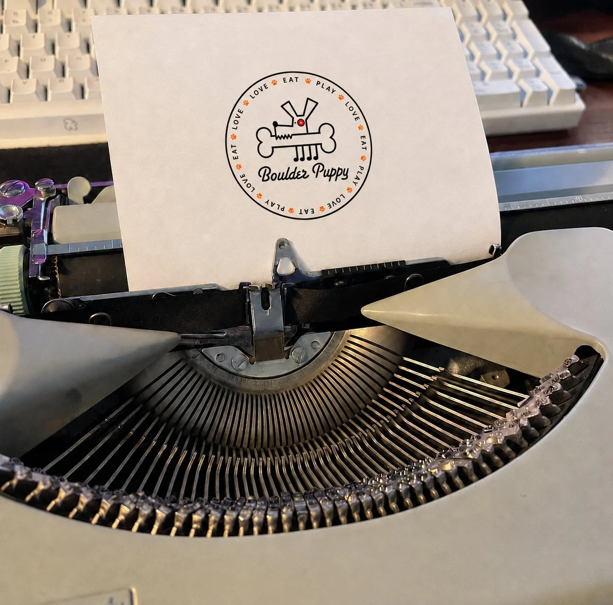 A sheet of paper in a typewriter, stamped with the Boulder Puppy logo