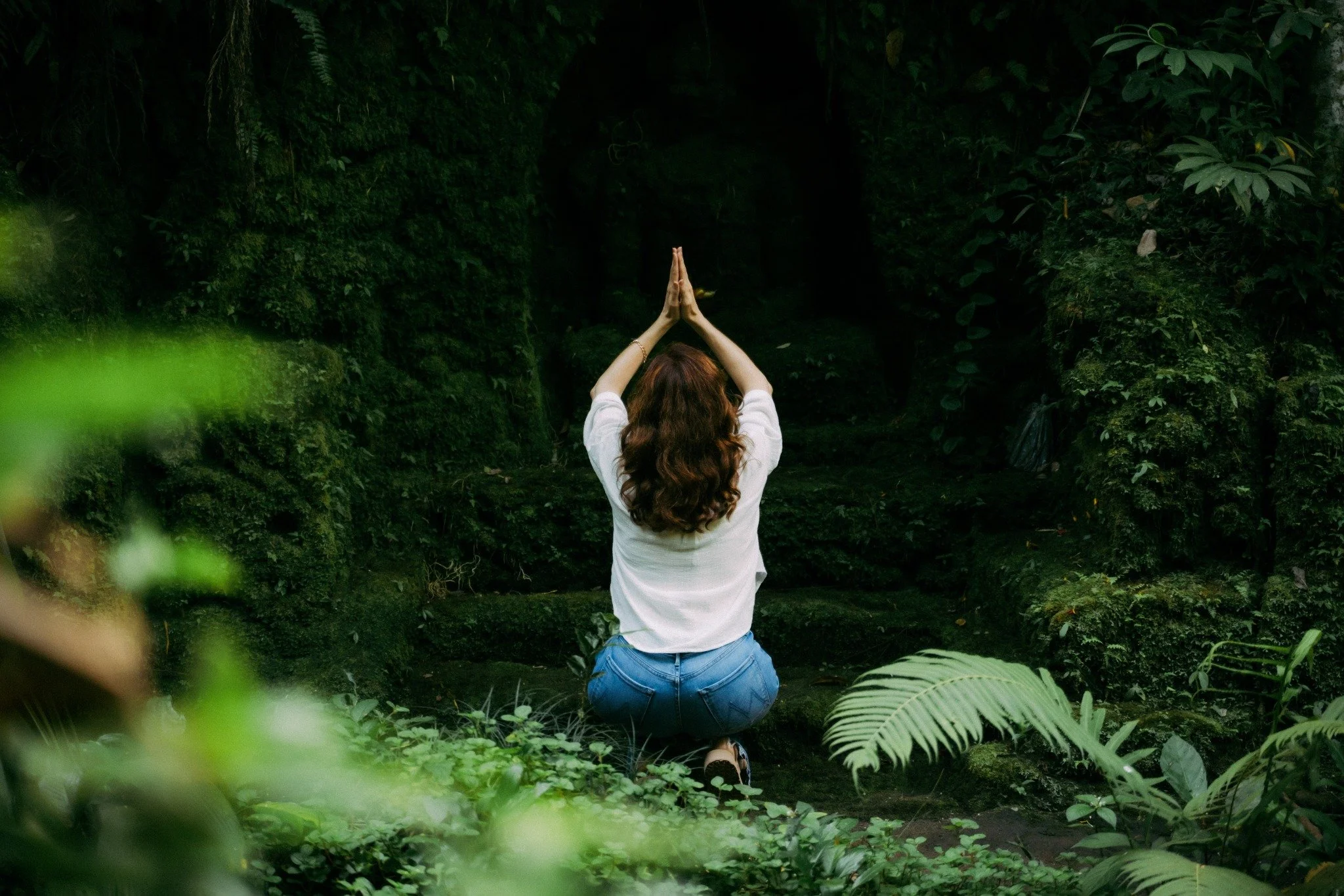 Anna Curran in a quiet yoga posture in a forest in Ubud